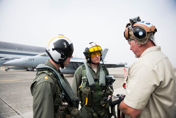 U.S. Air Force Lt. Col. Don Keen, 390th Electronic Combat Squadron commander, and Lt. Cmdr. Kerry Hicks, VAQ-129 EA-18G Growler pilot, receives a briefing before a flight in the EA-18G Growler at Naval Air Station Whidbey Island, Wash., August 7, 2014. Electronic attack missions are extremely complex and vital to providing cover for friendly aircraft during joint-combat operations. (U.S. Air Force photo by Airman 1st Class Malissa Lott/RELEASED)
