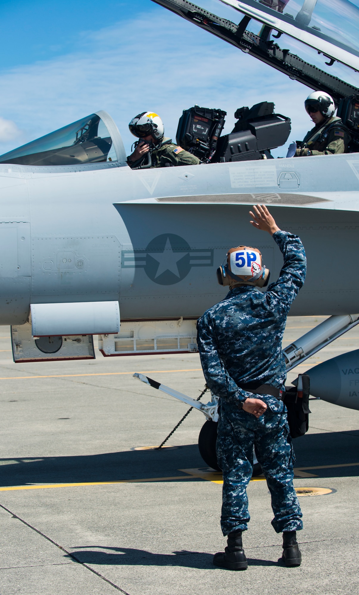 A Navy crew chief signals to the pilot and the electronic warfare officer during flight preparation at Naval Air Station Whidbey Island, Wash., August 6, 2014. Recently, the role of electronic attack has transitioned to the EA-18G Growler. (U.S. Air Force photo by Airman 1st Class Malissa Lott/RELEASED)