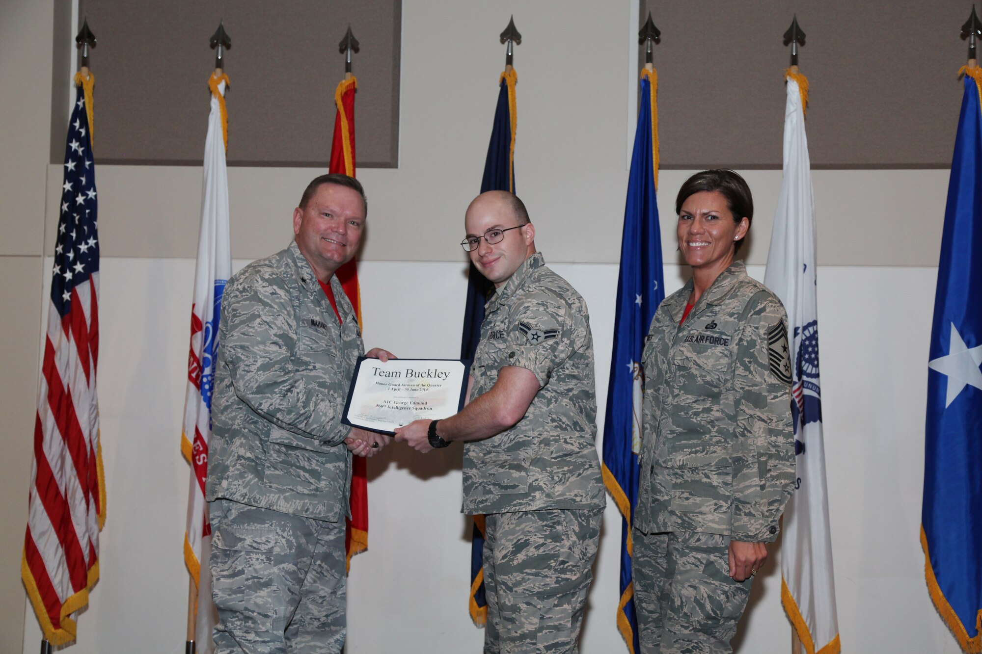 Brig. Gen. Samuel "Bo" Mahaney, Air Reserve Personnel Center commander, and Chief Master Sgt. Ruthe Flores, ARPC command chief, present the Honor Guard award to Airman 1st Class George Edmund, 566th Intelligence Squadron, during the Team Buckley quarterly awards ceremony Aug. 8 on Buckley Air Force Base, Colo. (U.S. Air Force photo/Quinn Jacobson)