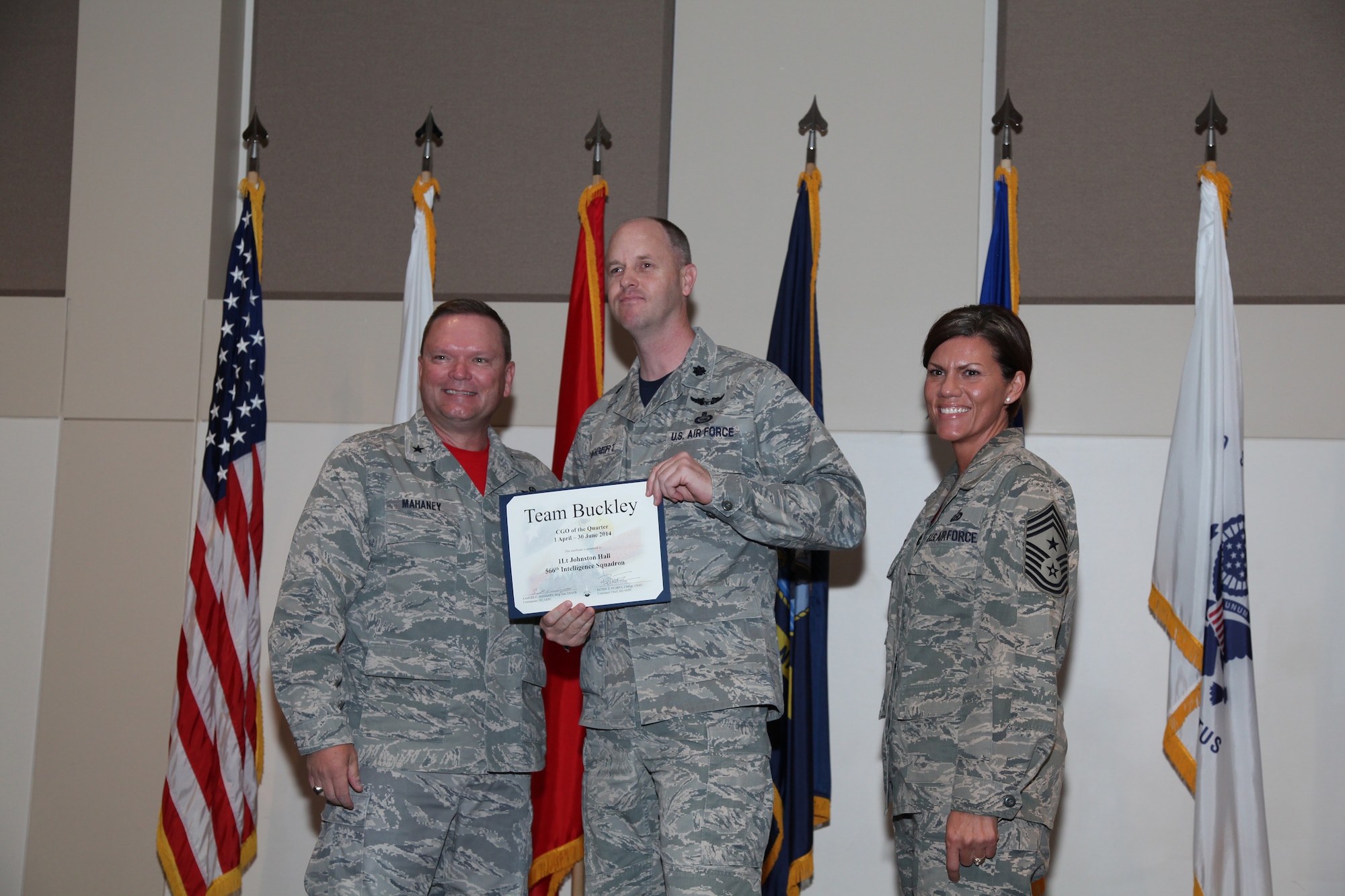 Brig. Gen. Samuel "Bo" Mahaney, Air Reserve Personnel Center commander, and Chief Master Sgt. Ruthe Flores, ARPC command chief, present the Company Grade Officer award to 1st Lt. Johnston Hall, 566th Intelligence Squadron, during the Team Buckley quarterly awards ceremony Aug. 8 on Buckley Air Force Base, Colo. (U.S. Air Force photo/Quinn Jacobson)
