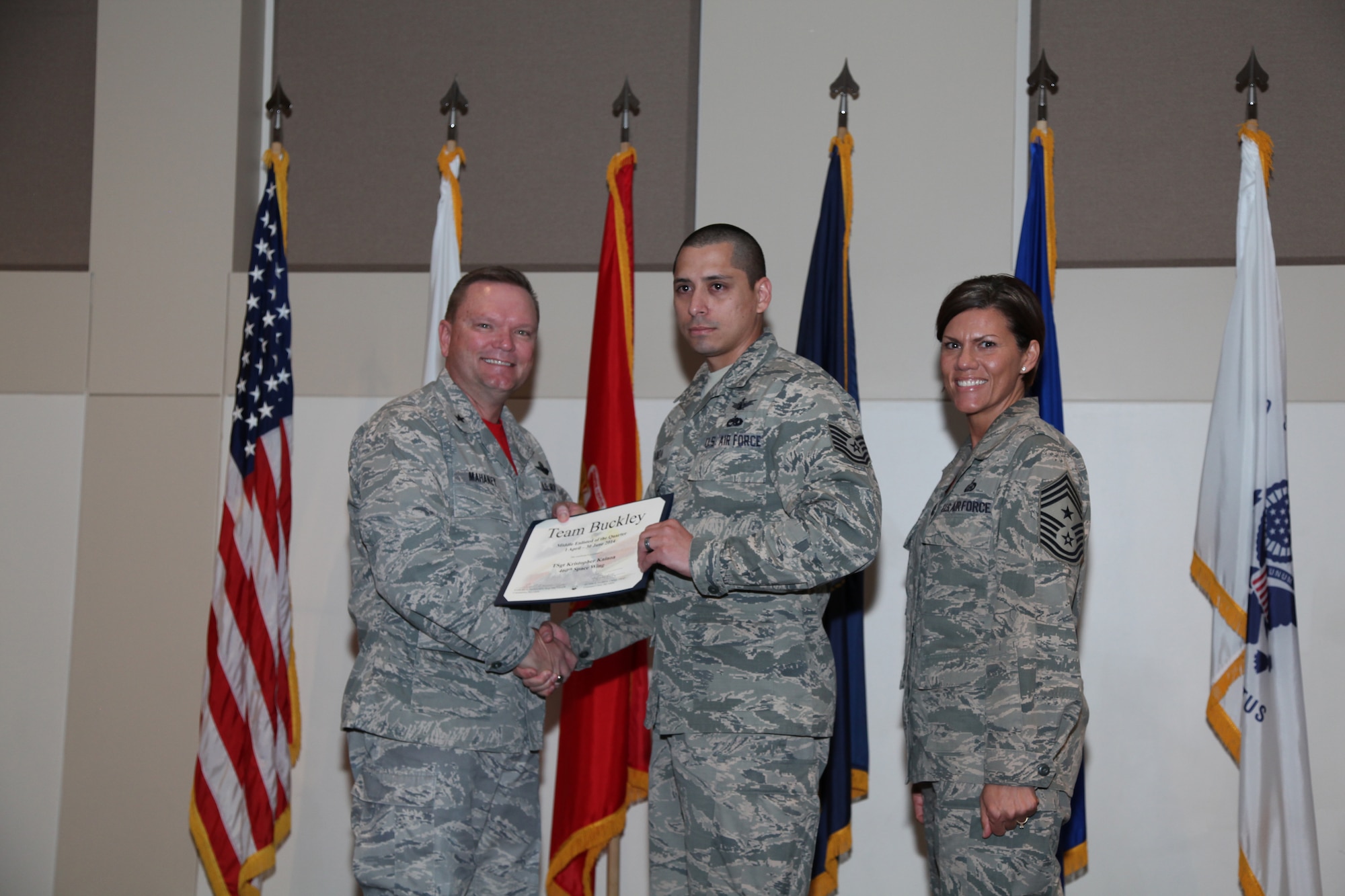 Brig. Gen. Samuel "Bo" Mahaney, Air Reserve Personnel Center commander, and Chief Master Sgt. Ruthe Flores, ARPC command chief, present the Middle Enlisted award to Tech. Sgt. Kristopher Kainoa, 460th Space Wing during the Team Buckley quarterly awards ceremony Aug. 8 on Buckley Air Force Base, Colo. (U.S. Air Force photo/Quinn Jacobson)
