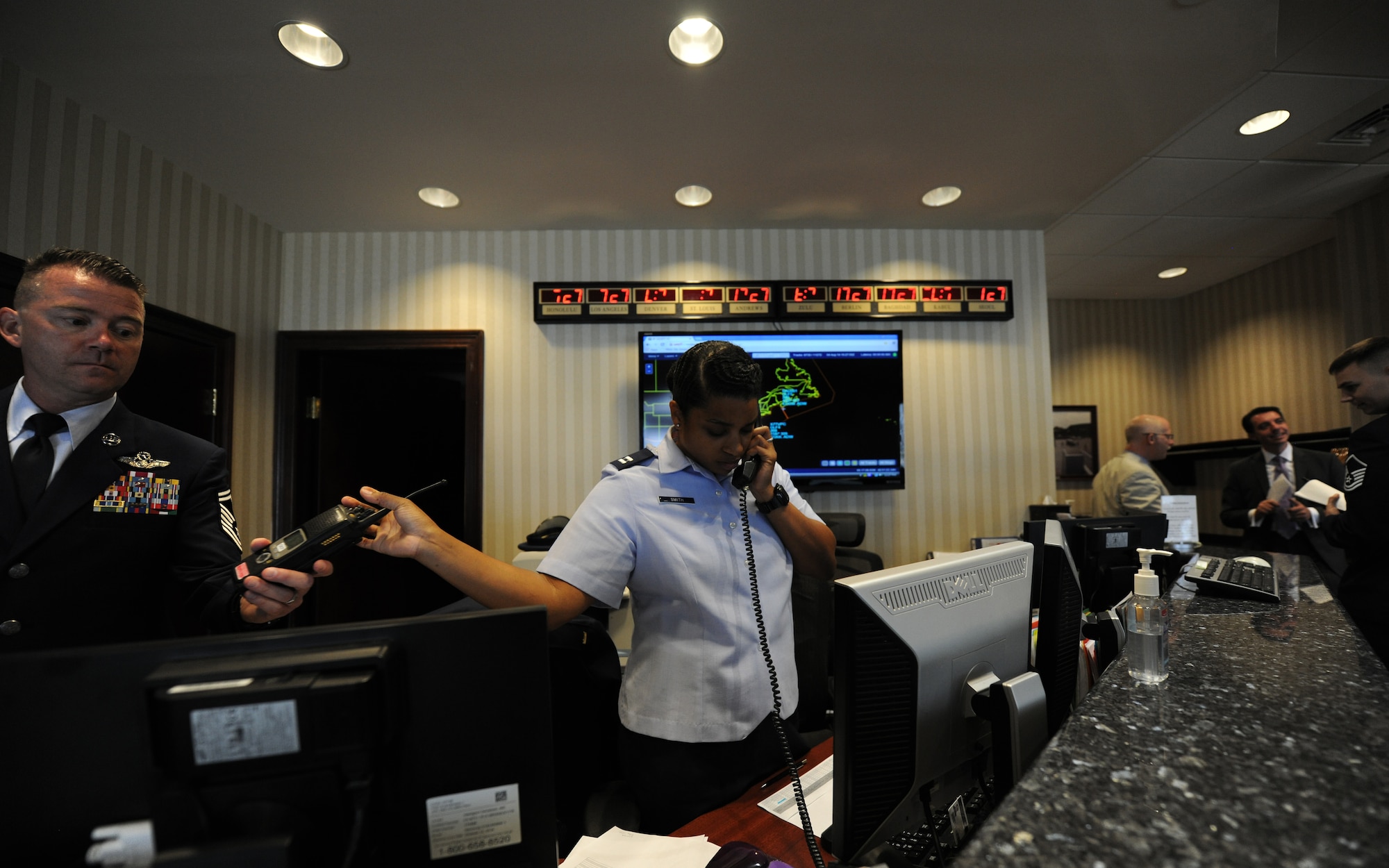 Captain Edith Smith hands a radio to Senior Master Sgt. Robert Casagrande at Joint Base Andrews distinguished visitors lounge, Md., August 3, 2014. Team Andrews collaborated with multiple organizations to ensure the safe arrival and departures of more than 20 aircraft arriving and departing for the U.S.-Africa Leaders Summit in Washington D.C.  Smith is the 89th Protocol’s deputy director and Casagrande is the superintendent. (U.S. Air Force photo/ Senior Airman Nesha Humes)