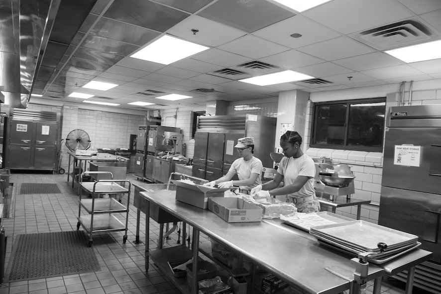 U.S. Air Force Senior Airman Erika Deaver, 23d Force Support Squadron services journeyman, left, and Airman 1st Class Neporsha Mobley, 23d FSS services journeyman, prepare meals at the Georgia Pines Dining Facility, Moody Air Force Base, Ga.,  Aug. 7, 2014. Deaver and Mobley prepare breakfast, lunch and dinner to feed more than 450 Airmen. (U.S. Air Force photo by Airman 1st Class Ceaira Tinsley/Released)