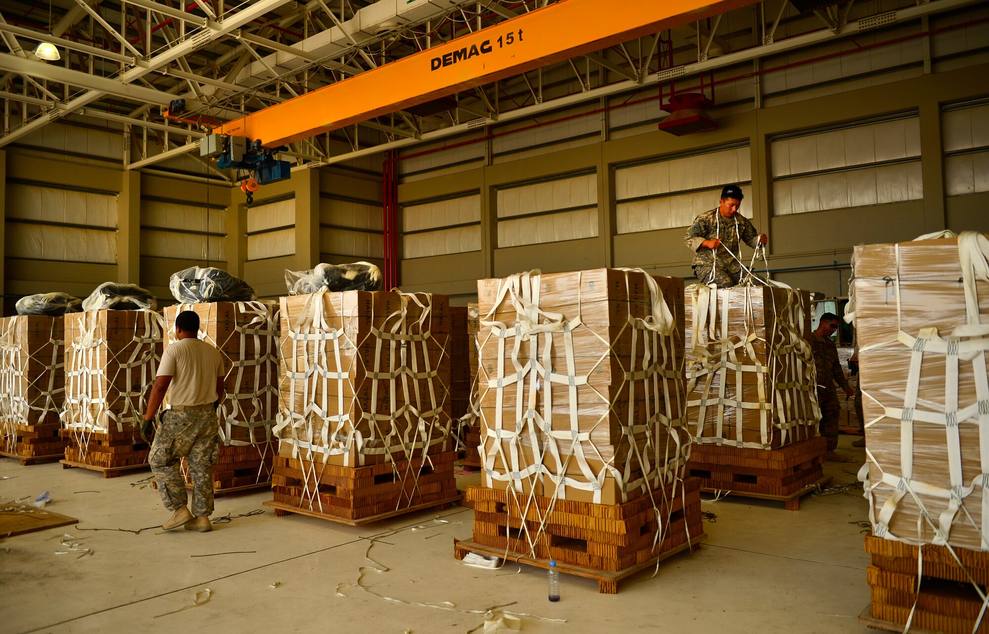 U.S. Army Soldier parachute riggers from the 11th Quartermaster Company, 264th Combat Sustainment Support Battalion, 82nd Sustainment Brigade, palletize halal meals for a humanitarian airdrop mission, Aug. 7, 2014, at a base in the U.S. Central Command area of responsibility. The humanitarian aid includes bottled water and food which was delivered to displaced citizens in the vicinity of Sinjar, Iraq. (U.S. Air Force photo by Staff Sgt. Vernon Young Jr.)