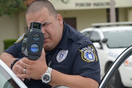 Marcelo Aguillon, a 902nd Security Forces Squadron officer, uses speed laser equipment to detect speeding on Joint Base San Antonio-Randolph, July 9, 2014. (U.S. Air Force photo by Joel Martinez)