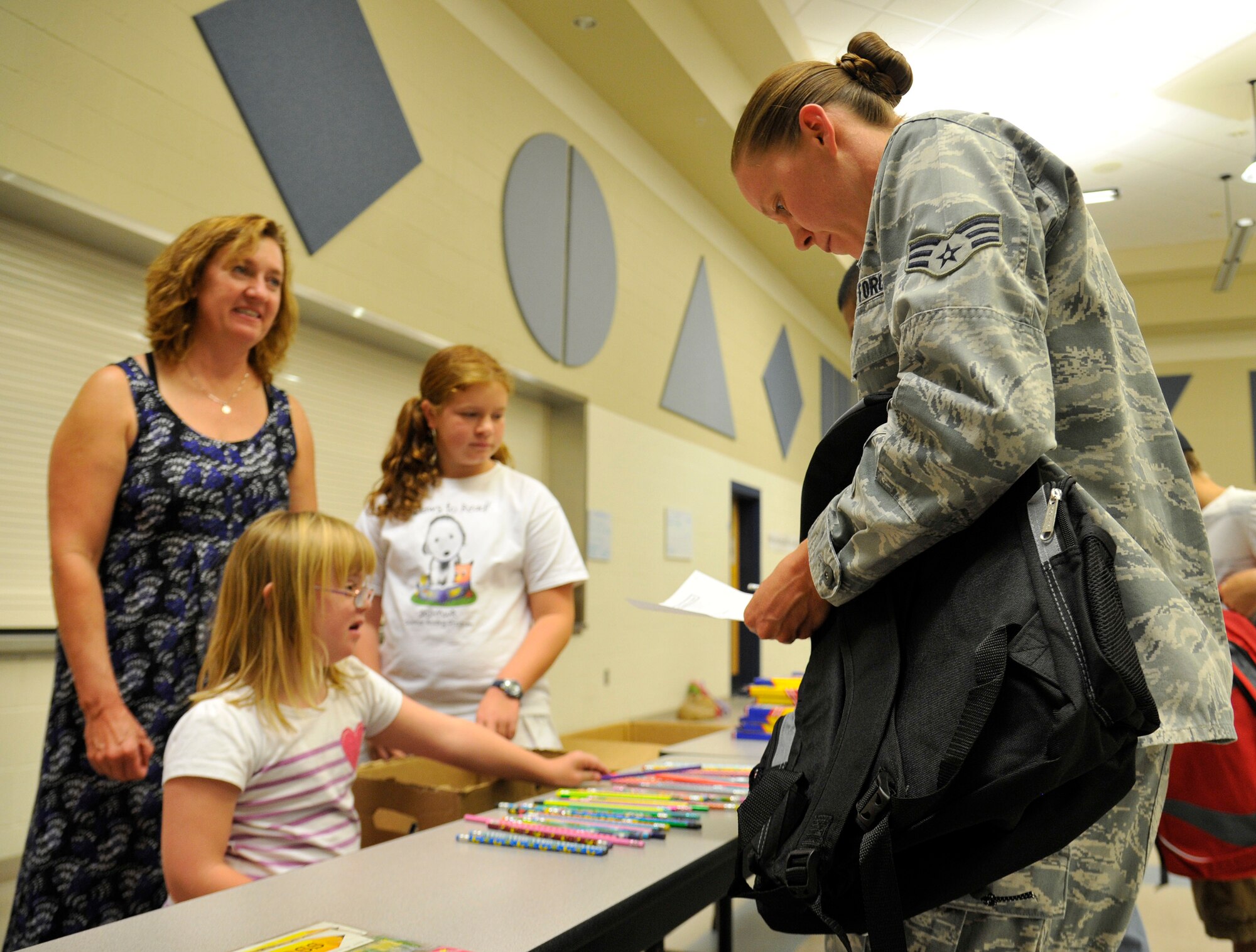Marlee McDaniel hands out school supplies to Senior Airman Laura Clay during Operation Homefront’s Back-to-School Brigade in the Michael Anderson Elementary School gymnasium at Fairchild Air Force Base, Washington, Aug. 7, 2014. Operation Homefront was formed in 2002 and since then has used 128 million dollars to help military families. Clay is a 92nd Logistics Readiness Squadron aircraft parts store journeyman. (U.S. Air Force photo by Senior Airman Ryan Zeski/Released)