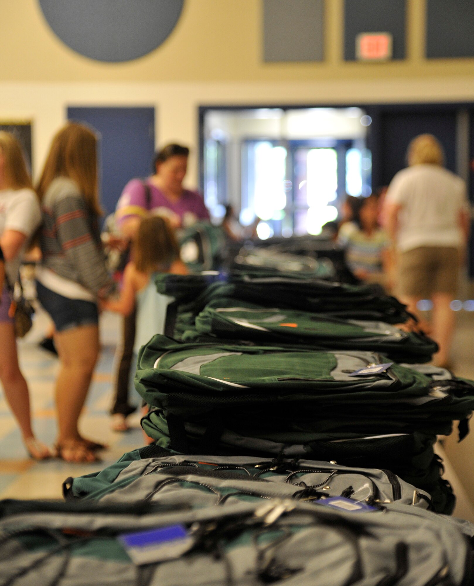 Family members of Team Fairchild pick out book bags during Operation Homefront’s Back-to-School Brigade in the Michael Anderson Elementary School gymnasium at Fairchild Air Force Base, Washington, Aug. 7, 2014. Operation Homefront was formed in 2002 and since then has used 128 million dollars to help military families. (U.S. Air Force photo by Senior Airman Ryan Zeski/Released)