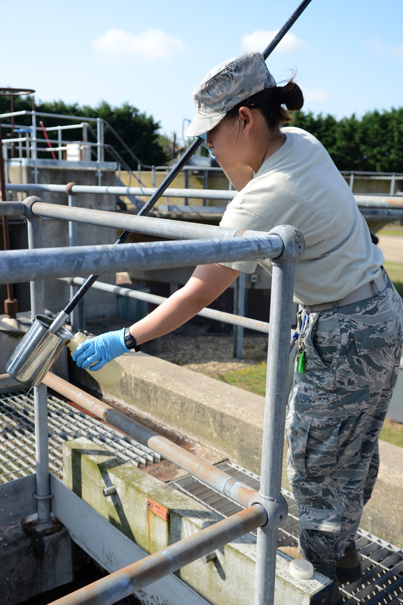U.S. Air Force Airman 1st Class Thao Chau, 100th Civil Engineer Squadron water and fuels systems maintenance apprentice, collects a water sample from the primary filter of the water processing plant Aug. 7, 2014, on RAF Mildenhall, England. Samples are collected from five different stages of the water filtration process and tested for substances which must be within a certain range to be deemed safe. (U.S. Air Force photo/Airman 1st Class Dillon Johnston/Released)