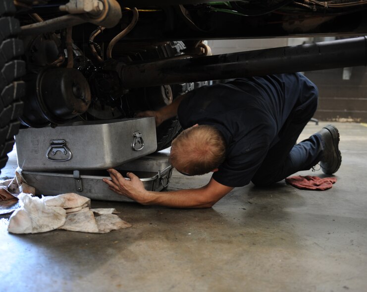 U.S. Air Force Senior Airman John Henry, 7th Logistics Readiness Squadron vehicle and vehicular maintenance journeyman, puts a drain pan underneath a dump truck Aug. 5, 2014, at Dyess Air Force Base, Texas. The use of the pans ensures that the fluid is collected to properly recycle. (U.S. Air Force photo by Airman 1st Class Kedesha Pennant/Released)