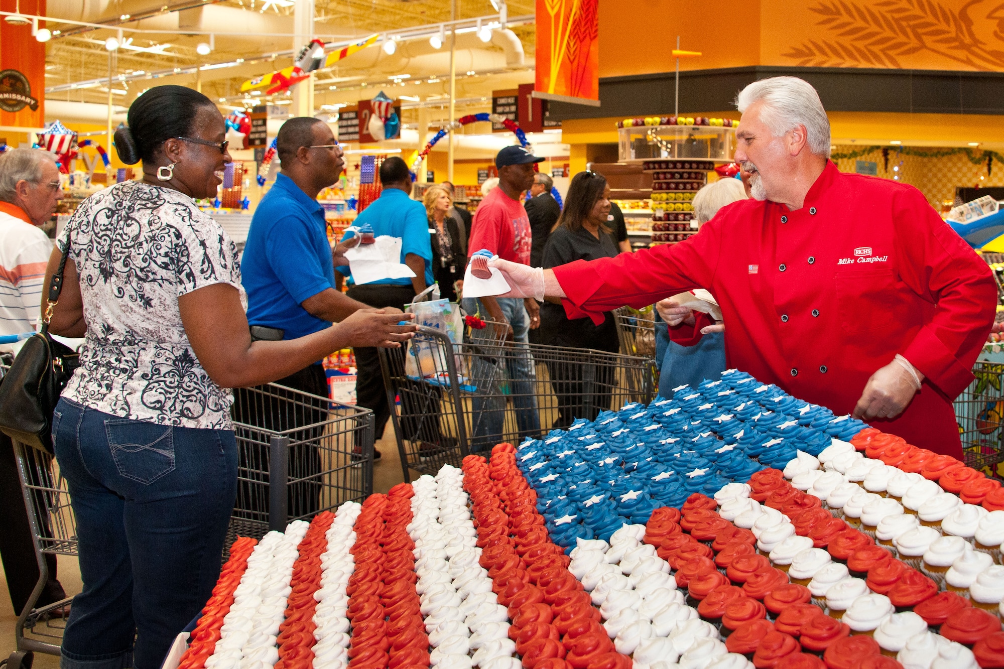 A Gunter-Annex commissary worker hands cupcakes out to customers at the store’s grand opening Aug. 5, 2014. The commissary was approximately a year in the making and boasts a larger more energy efficient store than the previous commissary, which was built in 1974. (U.S. Air Force photo by Donna L. Burnett)