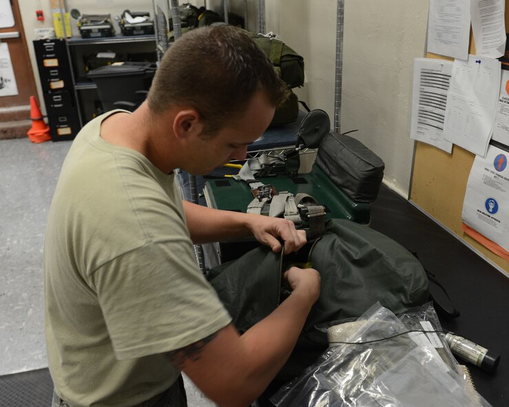 Staff Sgt. Cody Markham, 2nd Operations Support Squadron Aircrew Flight Equipment parachute section, packs a survival kit on Barksdale Air Force Base, La., Aug. 4, 2014. The kits include life-saving equipment in the event of an egress to include flares, a strobe light, tourniquet, knife and water. (U.S. Air Force photo/Senior Airman Benjamin Gonsier)