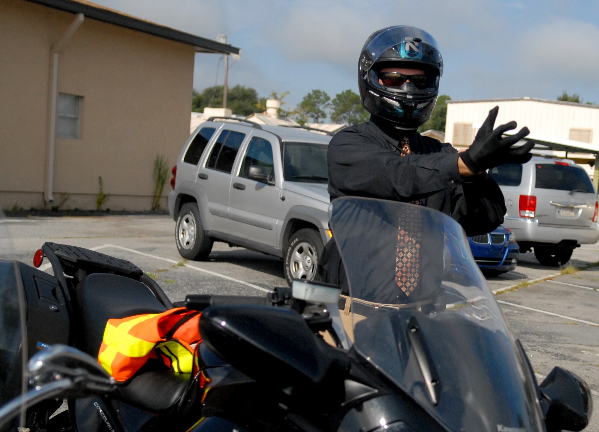 John Ainsworth, Robins Safety Office safety and occupation health specialist, puts on his protective gear prior to riding on base, Aug. 4, 2014. Riders must wear a Department of Transportation-approved helmet, full-fingered gloves, long-sleeve shirt of jackets, long pants, eye and foot protection. (U.S. Air Force photo by Misuzu Allen)
