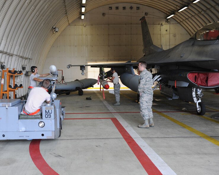 U.S. Air Force aircraft armament specialists from the 480th Aircraft Maintenance Unit load training munitions onto a U.S. Air Force F-16 Fighting Falcon fighter aircraft during a base exercise Aug. 6, 2014, at Spangdahlem Air Base, Germany. Standardization crew members inspected the 480th AMU to ensure they maintain safety and follow protocol. (U.S. Air Force photo by Airman 1st Class Dylan Nuckolls/Released)