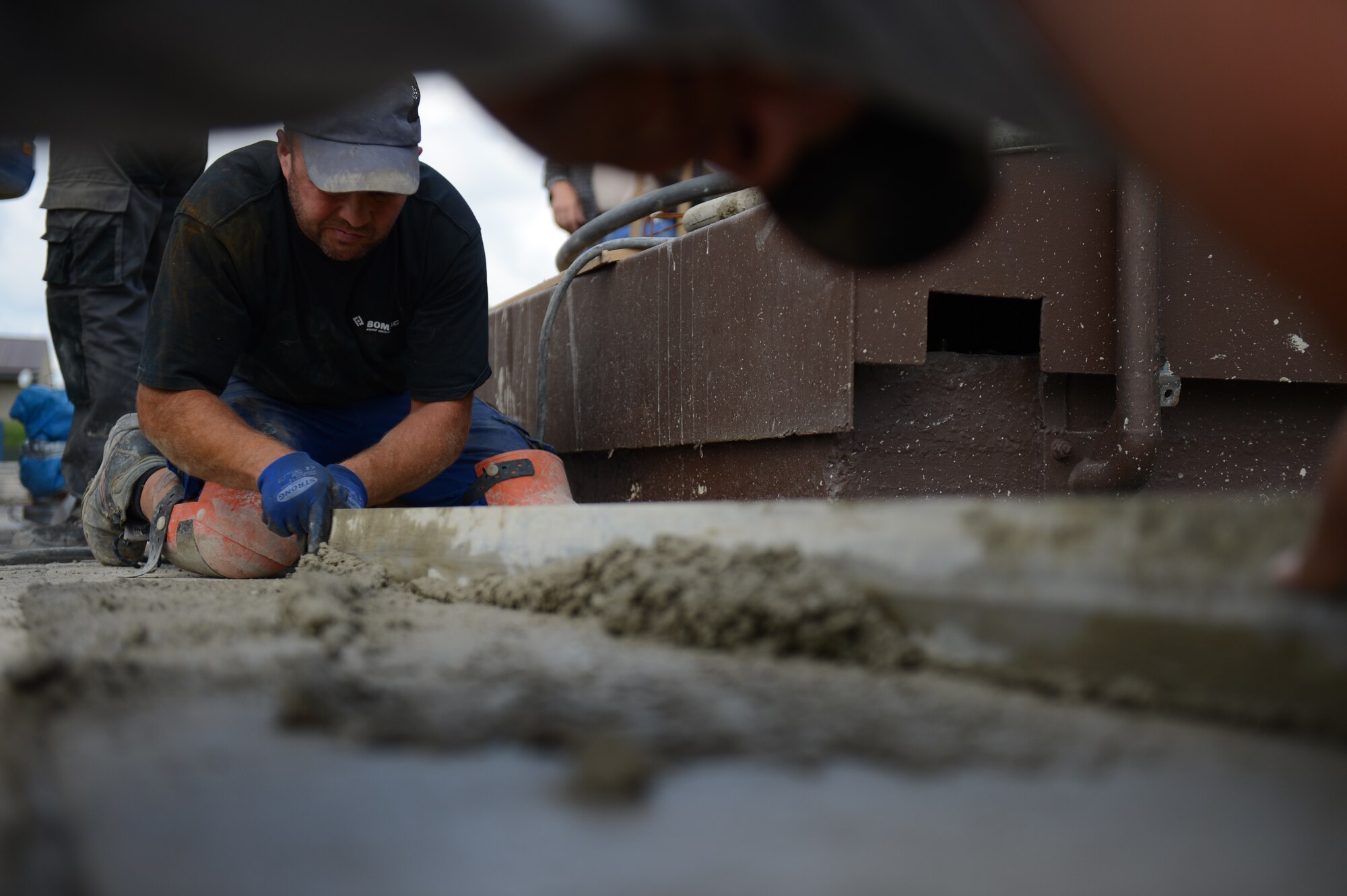 Thorsten Klinkosch, German contractor, removes excess concrete during construction on the flightline at Spangdahlem Air Base, Germany, Aug. 7, 2014. The workers will pour approximately 1,000 cubic meters of concrete over the course of the construction. (U.S. Air Force photo by Senior Airman Gustavo Castillo/Released)