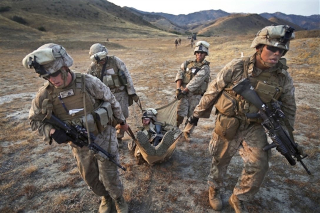 Marines carry a simulated casualty after performing a live-fire defense against an enemy counterattack on Camp Pendleton, Calif., July 31, 2014. The Marines, assigned to Lima Company, 3rd Battalion, 1st Marine Regiment, trained to sharpen their skills during enemy assaults while receiving support from integrated machine guns and mortars. 