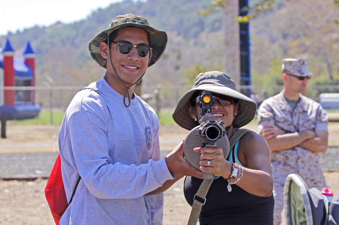 Mark Anthony Reina and Priscilla Reina handle a multiple grenade launcher from a static display during a Jane Wayne Day event at the School of Infantry here, Aug. 9.

The day started off with one group breaking off to learn how to operate different weapons systems such as the M16 service rifle and the M9 service pistols using the Indoor Simulated Marksmanship Trainer. They travelled to Range 210C to conduct a live-fire shoot with the M27 Infantry Automatic Rifle.

"It was a fun experience," said Kaylee Walter, whose husband serves as the executive officer for India Company, Marine Combat Training Battalion, SOI-W. "It was surprising how heavy the weapon was and how hard it was to hit the target. It really gave me a whole new understanding and appreciation as to what my husband does."