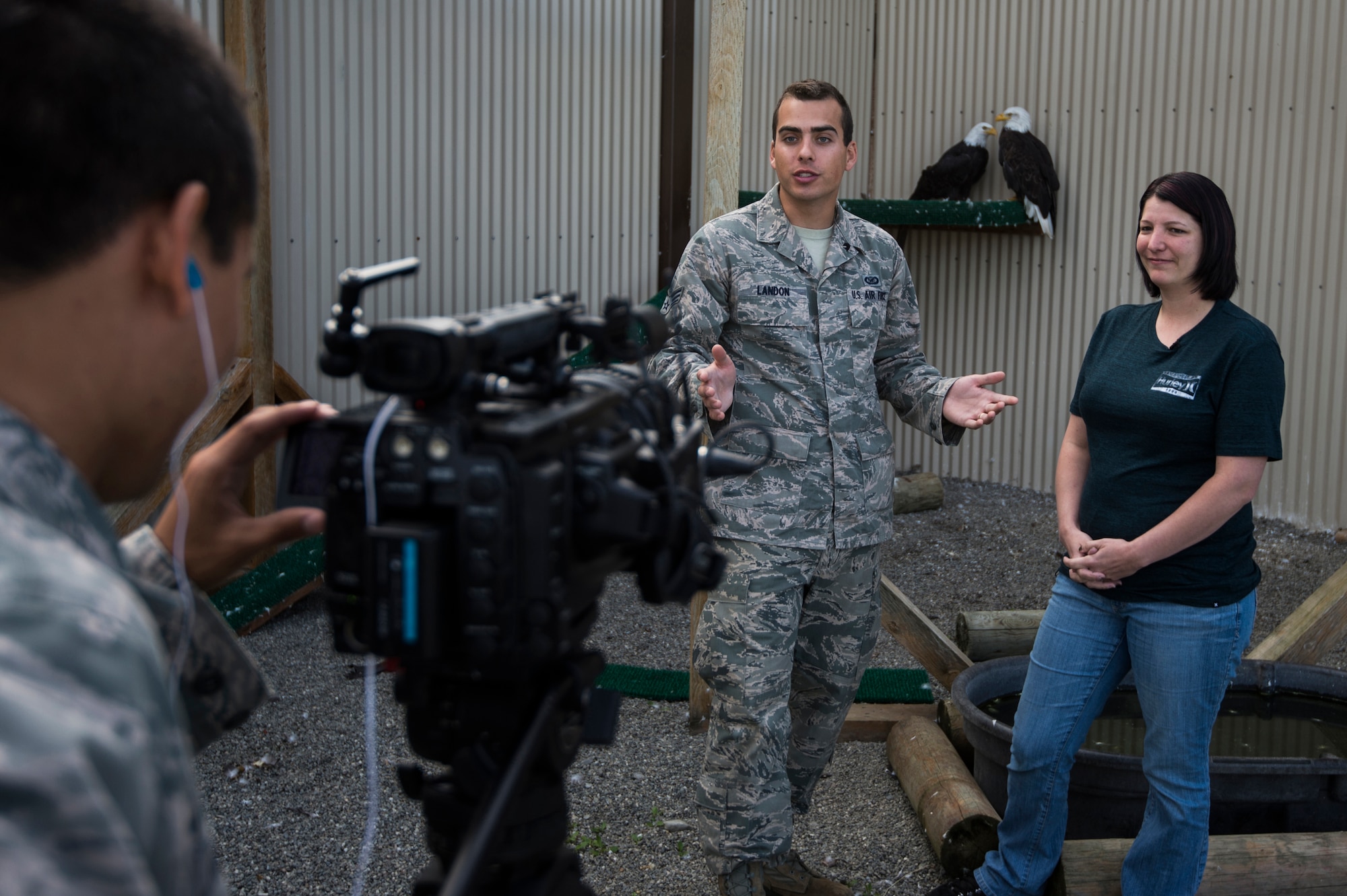 U.S. Air Force Senior Airman Benjamin Landon and Airman 1st Class Danny Rangel, 2nd Combat Camera Squadron broadcasters, interview Michelle Hartman, coordinator for the bald eagle aviary, at Joint Base Elmendorf-Richardson, Alaska, Aug. 6, 2014.  The aviary is run by mostly military volunteers and is a sanctuary for injured bald eagles that can't survive in the wild. (U.S. Air Force photo by Staff Sgt. Stephany Richards/ Released)