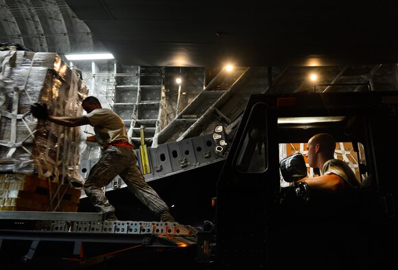 Staff Sgt. Daniel Leavindofske, 8th Expeditionary Air Mobility Squadron ramp team chief and Senior Airman David Babcock, air transportation journeyman, assist with loading 28,224 halal meals to a C-17 Globemaster III for a humanitarian airdrop mission over Iraq, Aug. 9, 2014, at a base in the U.S. Central Command area of responsibility. The humanitarian aid includes bottled water and food which was delivered to displaced citizens in the vicinity of Sinjar, Iraq. (U.S. Air Force photo by Staff Sgt. Vernon Young Jr.)