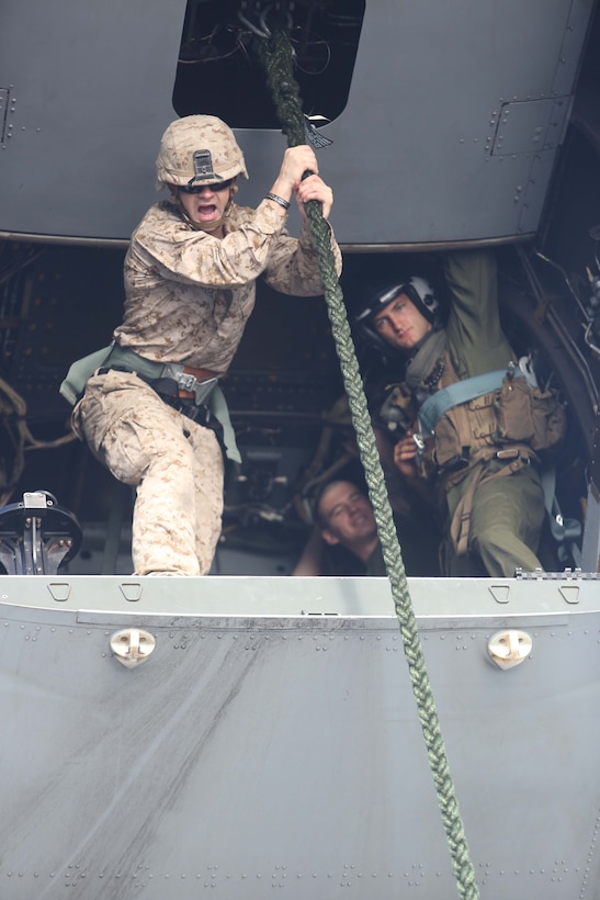 A Marine with Weapons Company, Battalion Landing Team 2nd Battalion, 1st Marines, 11th Marine Expeditionary Unit, coaches Marines down a rope as part of a fast rope qualification during the 11th MEU’s WESTPAC 14-2 deployment, aboard the USS Makin Island  Aug. 8, 2014. The 11th MEU and Makin Island Amphibious Ready Group are deployed as a sea-based, expeditionary crisis response force capable of conducting amphibious missions across the full range of military operations. (U.S. Marine Corps photo by Lance Cpl. Evan R. White/Released)