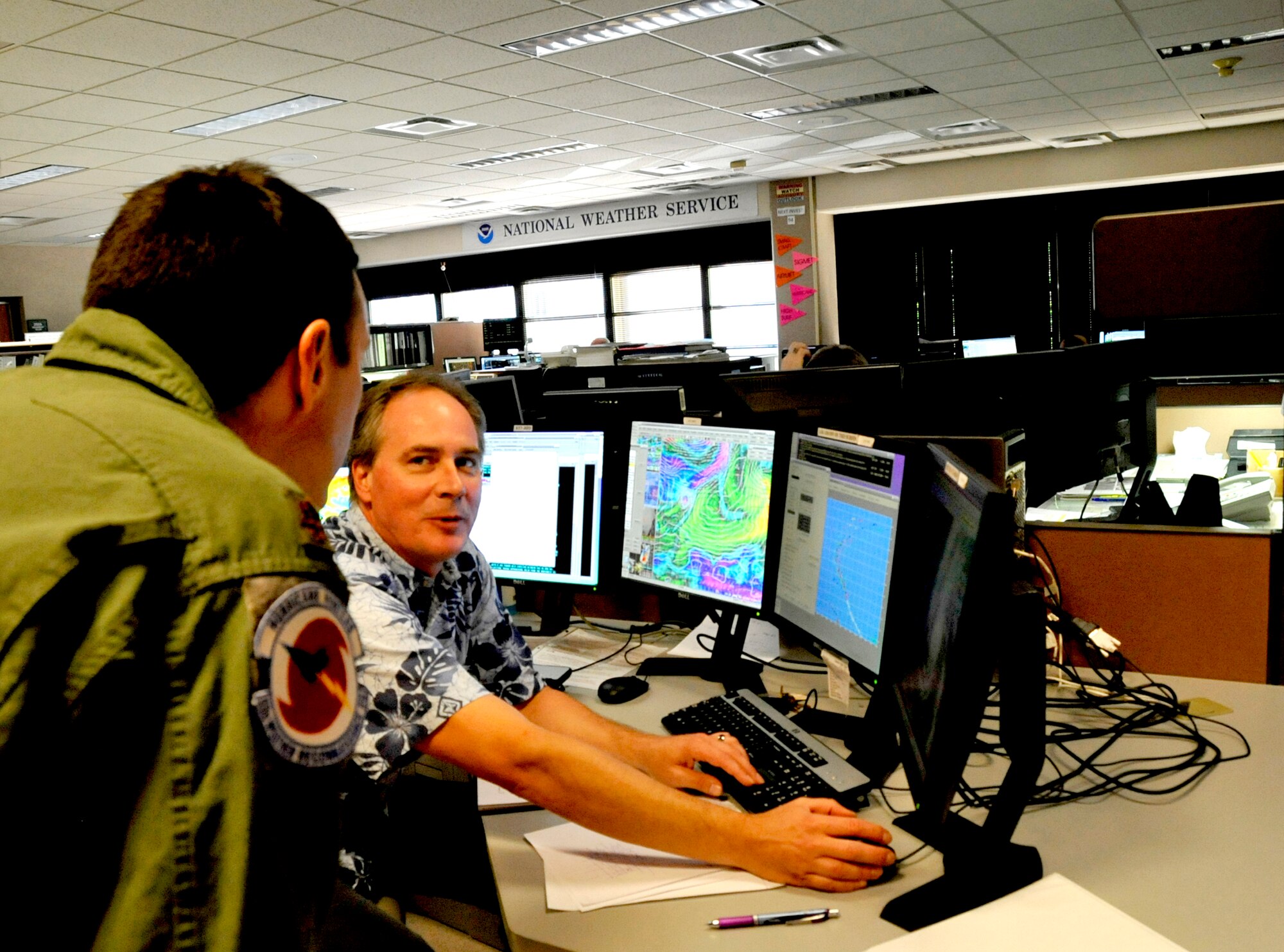 Thomas Birchard, senior forcaster and hurricane expert for the Central Pacific Hurricane center, shows Maj. Jon Brady, a aerial reconnaissance weather officer, computer programs used to predict a hurricane model from the weather data collected by the 53rd Weather Reconnaissance Squadron through hurricanes.  The 53rd WRS "Hurricane Hunters" aircrew and 403rd Wing maintenance personnel deployed to Hickam Air Force Base, Hawaii to fly storm missions into Hurricanes Iselle and Julio.  The "Hurricane Hunters" fly storm missions in both the Atlantic and Pacific Oceans during the hurricane season which offically starts June 1 and ends Nov. 30 yearly. (U.S. Air Force photo by Master Sgt. Jessica Kendziorek)  
