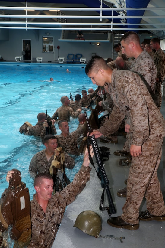 Marines with Weapons Company, 1st Battalion, 24th Marine Regiment, assist each other out of the pool during water survival qualification as part of their annual training during Exercise Heavy Metal 2014 at Marine Corps Base Camp Lejeune, North Carolina Aug. 11, 2014. This portion of the course requires the Marines to enter the water wearing a vest, helmet and rifle then submerge themselves and remove all the equipment in a predetermined time limit.  (U.S. Marine Corps photo by Cpl. J. Gage Karwick)