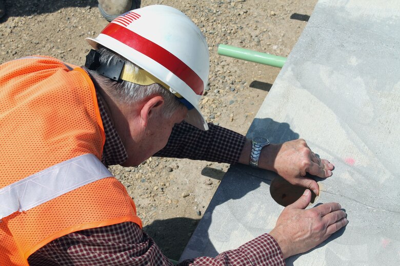 Throughout the Minot Air Force Base runway replacement project’s construction, the prime contractor, Sundt, has taken core samples from various paving sections to ensure that the concrete meets the stringent design specifications that are aimed at providing a runway that will provide another 50 years of service. Here a consultant with the U.S. Air Force inspects the aggregate distribution at a hole drilled during the core sampling process.