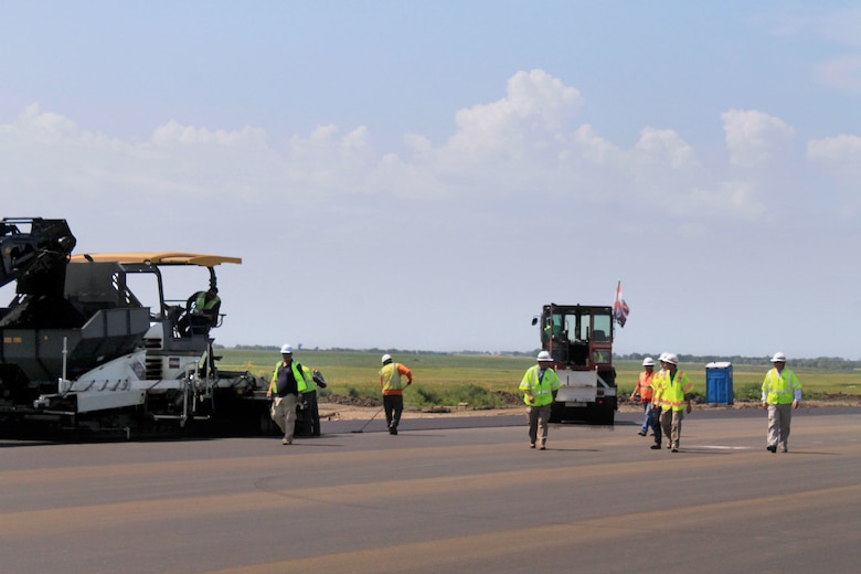 Asphalt paving crews at Minot Air Force Base, N.D., are using a three-wheeled roller for initial asphalt compaction providing tight joint compaction between the concrete and asphalt.