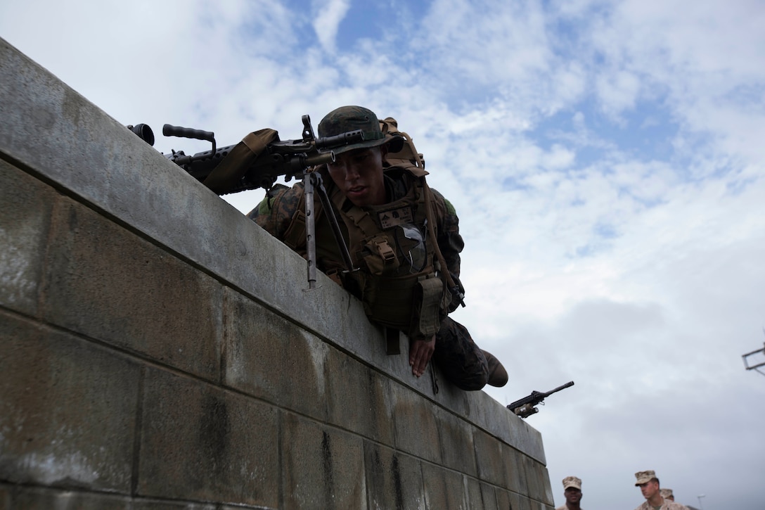 Lance Corporal Rashon Burrell, an automatic rifleman with Company K, Battalion Landing Team 3rd Battalion, 5th Marines, 31st Marine Expeditionary Unit, and a native of Waterloo, Iowa, climbs over a wall as part of a squad competition at Camp Hansen, Aug. 8. The competition started at 5 a.m. with one squad starting every twenty minutes. There were seven total stations the BLT Marines had to complete, which included a physical circuit course where the Marines performed squad pushups, jumping lunges and air squats. Another station challenged the Marines to answer infantry-related questions for points that helped toward their overall time.  They concluded the competition with a swim before using their rifles to shoot at targets while moving from position to position. The 31st MEU is the force of choice for the Asia-Pacific region and is the only continuously forward-deployed MEU. 