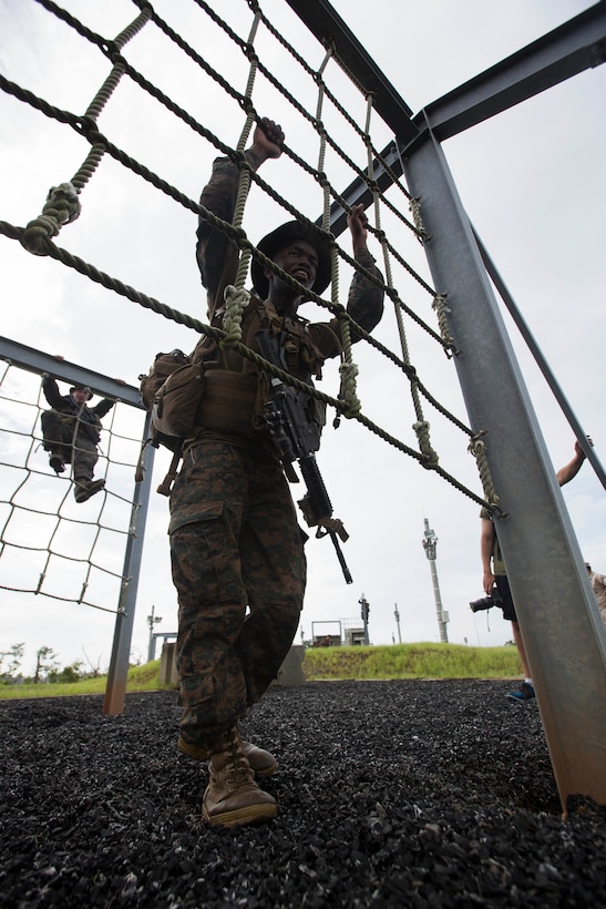 Lance Corporal Marlon Fedd, a rifleman with Company K, Battalion Landing Team 3rd Battalion, 5th Marines, 31st Marine Expeditionary Unit, and a native of Irvine, California, prepares to climb a net as part of a squad competition at Camp Hansen, Aug. 8. The competition started at 5 a.m. with one squad starting every twenty minutes. There were seven total stations the BLT Marines had to complete, which included a physical circuit course where the Marines performed squad pushups, jumping lunges and air squats. Another station challenged the Marines to answer infantry-related questions for points that helped toward their overall time.  They concluded the competition with a swim before using their rifles to shoot at targets while moving from position to position. The 31st MEU is the force of choice for the Asia-Pacific region and is the only continuously forward-deployed MEU. 