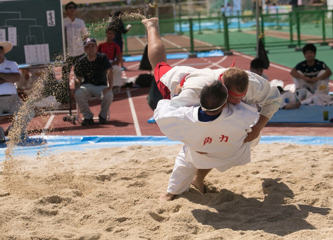 Lance Cpl. Scott G. Gulette, top, catches his opponent off-guard and brings him to the ground during the 35th annual Okinawa Island-Wide Sumo Tournament July 26, 2014 at the Kin Town Athletic Field, Okinawa, Japan. In Okinawa-style sumo wrestling, the competitors begin at the center of the ring with both hands on their opponent’s belt and they attempt to pin their opponents to the ground without losing their grip. Gulette is a Richmond, Michigan native and forward observer with 5th Air Naval Gunfire Liaison Company, III Marine Expeditionary Force Headquarters Group, III MEF.