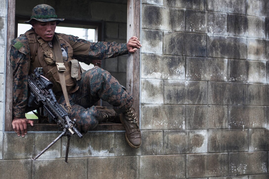 Lance Cpl. Rashon Burrell, an automatic rifleman with Company K, Battalion Landing Team, 3rd Battalion, 5th Marine Regiment, 31st Marine Expeditionary Unit, a Waterloo, Iowa native, maneuvers through a window as part of a squad competition at Central Training Area, Camp Hansen, Okinawa, Japan, Aug. 8, 2014. There were seven total stations the BLT Marines had to complete, which included a physical circuit course where the Marines performed squad push ups, jumping lunges and air squats. Another station challenged the Marines to answer infantry-related questions for points that helped toward their overall time. The competition started at 5 a.m., with one squad starting every twenty minutes.