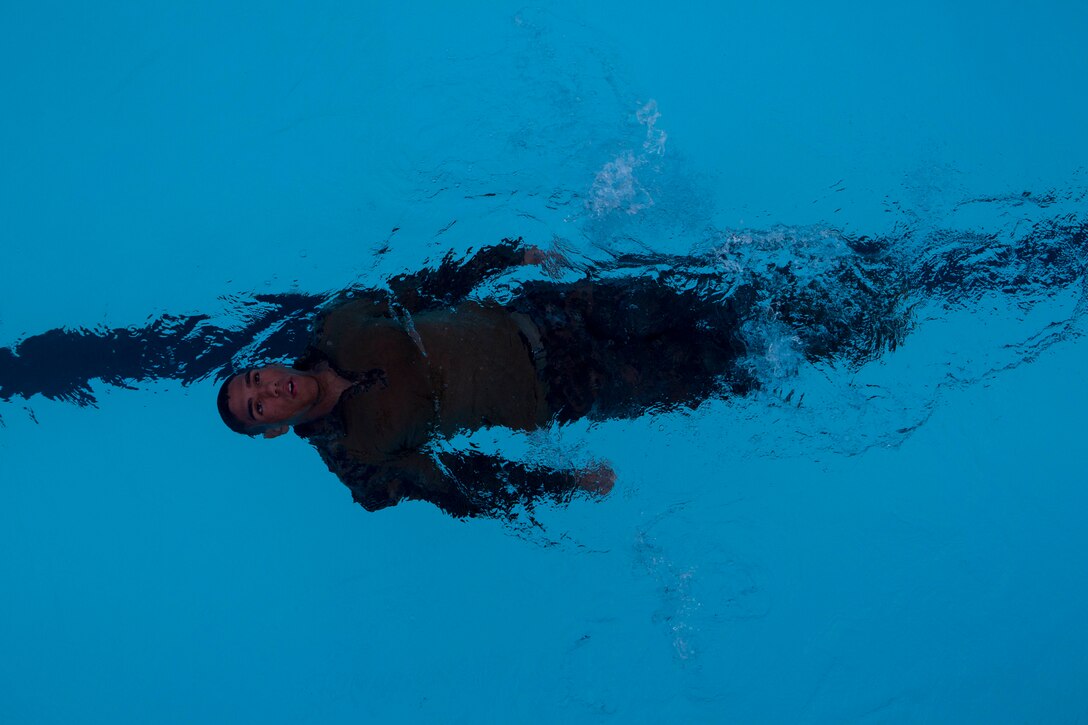 Lance Cpl. Rashon Burrell, an automatic rifleman with Company K, Battalion Landing Team 3rd Battalion, 5th Marine Regiment, 31st Marine Expeditionary Unit and a native of Waterloo, Iowa, swims on his back as part of a squad competition at Camp Hansen, Okinawa, Aug. 8, 2014. There were seven total stations the BLT Marines had to complete, which included a physical circuit course where the Marines performed squad pushups, jumping lunges and air squats. Another station challenged the Marines to answer infantry-related questions for points that helped toward their overall time. The competition started at 5 a.m., with one squad starting every twenty minutes.