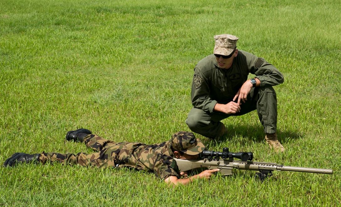 Lance Cpl. Hunter Freeman, top, discusses the M110 semi-automatic sniper system with Japan Air Self-Defense Force Staff Sgt. Akinori Kobayashi Aug. 5, 2014 during a visit by Japan Self-Defense Force service members to the Provost Marshal’s Office on Camp Foster. The JSDF members spent the day touring PMO and observing the equipment they use. Freeman is a Savannah, Georgia native and SRT entry team member with PMO, Marine Corps Base Camp Butler, Marine Corps Installations Pacific. Kobayashi is a Naha City, Okinawa, native and security guard with 83rd Air Wing, Naha Air Base.