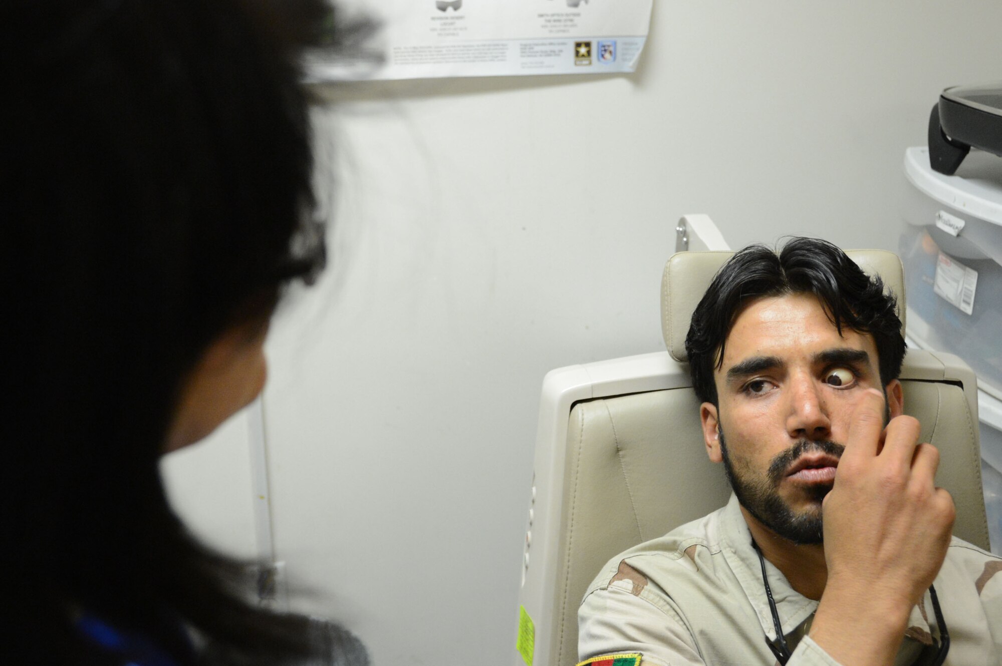 An Afghan interpreter listens to an Afghan soldier while he tells her of the discomfort of a prosthetic eye that was just placed in his left eye socket while receiving treatment at the Craig Joint Theater Hospital at Bagram Airfield, Afghanistan Aug. 7, 2014. The soldier suffered an eye trauma when shrapnel from an explosion hit him in his eye four months ago. Price is a native of Goldsborough, N.C. and deployed form the 4th Aerospace Medicine Squadron at Seymour Johnson, Air Force Base, N.C. (U.S. Air Force photo by Master Sgt. Cohen A. Young/Released)