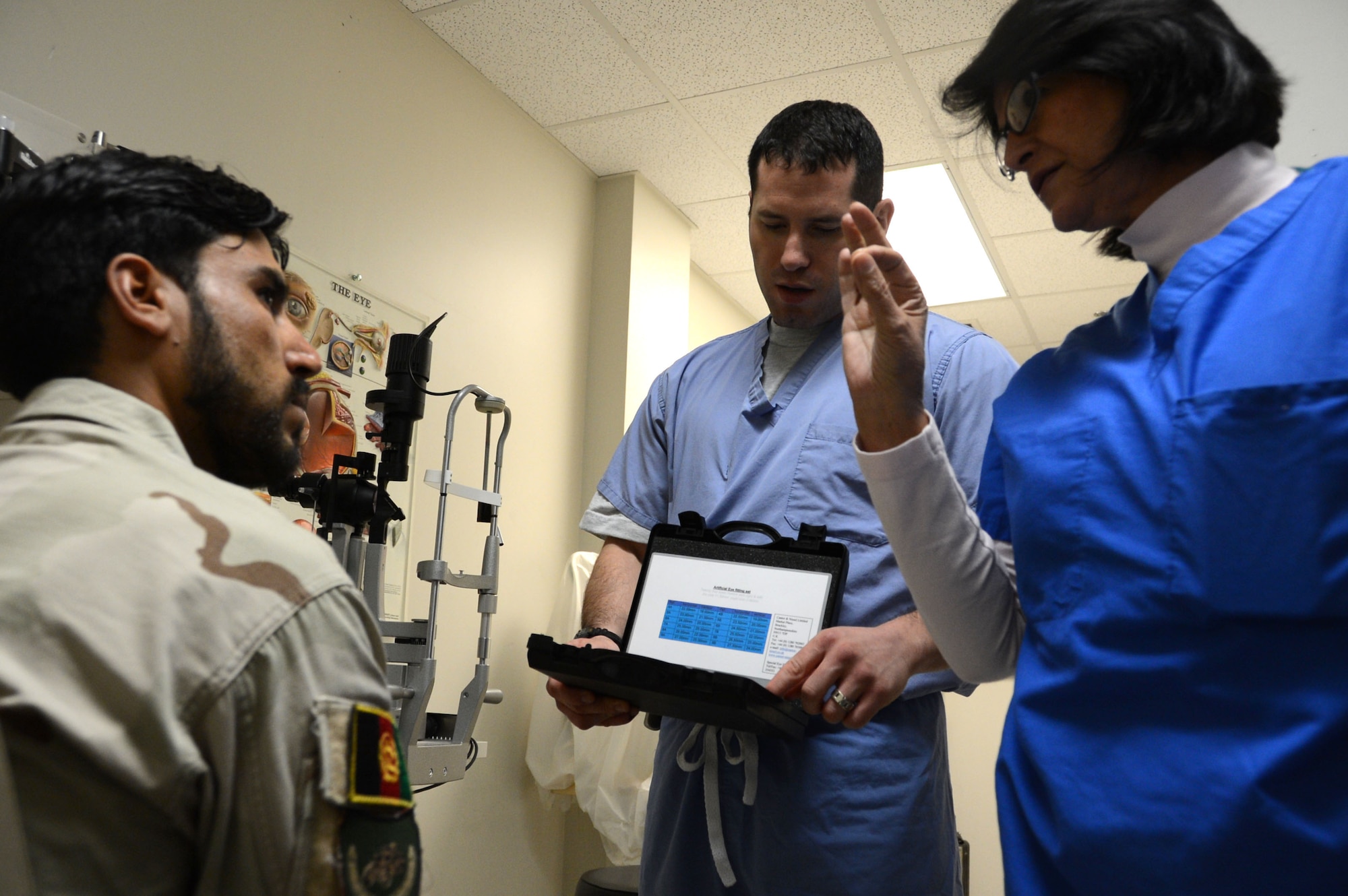 U.S. Air Force Maj. Michael Parsons, an ophthalmologist assigned to the 455th Expeditionary Medical Group, looks through a container of prosthetic eyeballs while an Afghan soldier listens to an interpreter explain the process of ocular prosthesis while at the Craig Joint Theater Hospital at Bagram Airfield, Afghanistan Aug. 7, 2014. The soldier suffered an eye trauma when shrapnel from an explosion hit him four months ago. Parsons is a native of Poughkeepsie, N.Y. and deployed form the 88th surgical squadron at Wright-Patterson Air Force Base, Ohio. (U.S. Air Force photo by Master Sgt. Cohen A. Young/Released)