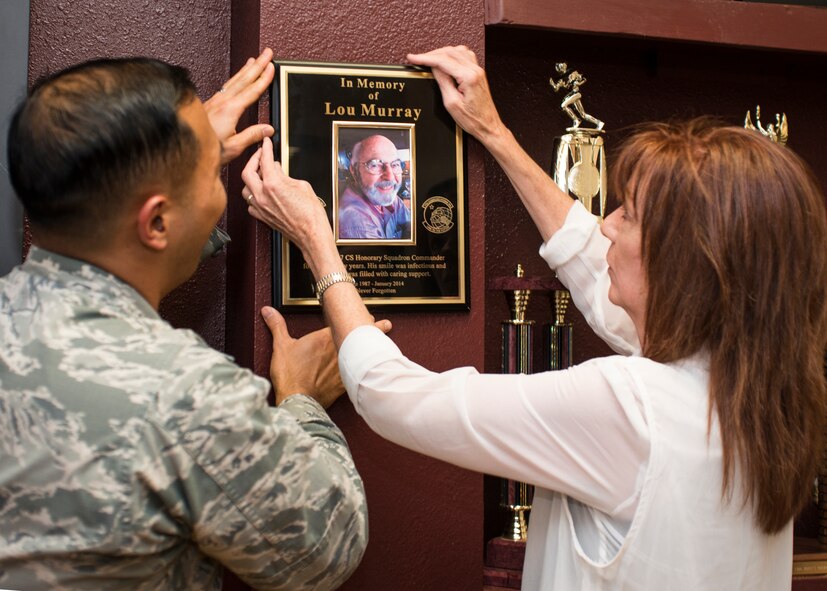 U.S. Air Force Maj. Kyle Takamura, 7th Communication Squadron commander, and Mrs. Rhonna Murrey, wife of the late Lou Murray, former 7th CS honorary commander, hangs a plaque in commemoration of Lou Murray’s contribution as the 7th CS honorary commander August 7, 2014, at Dyess Air Force Base, Texas. Lou Murray served as the Honorary Commander for the 7th CS for 27 years. Before Lou became ill he would often participate in unit events or visit the squadron simply to give out treats and speak with the Airmen. The honorary commander program is designed to help local business and civic leaders gain a more complete understanding of the day-to-day operations of an Air Force base. Lou Murray passed away on April 13, 2014. (U.S. Air Force photo by Senior Airman Peter Thompson/Released)