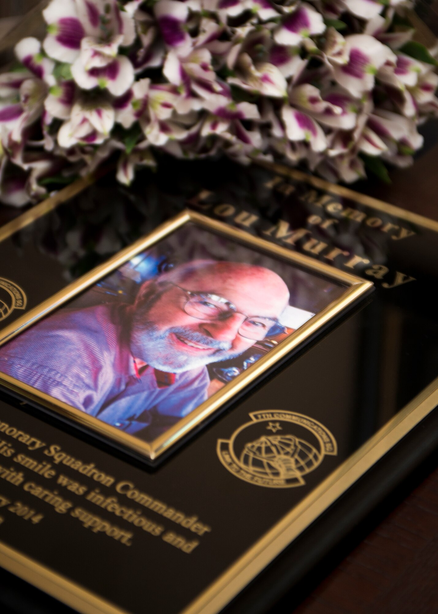 A plaque commemorating Lou Murray’s 27 years of service to the 7th Communication Squadron as their honorary commander lies on a table August 7, 2014, at Dyess Air Force Base, Texas. Before relinquishing his position in April of 2014, Lou Murray was known for always bringing great energy and smiles to the Airmen in his Squadron. Honorary commanders attend various base/squadron events to become knowledgeable of their assigned unit’s mission and challenges. The plaque commemorating his time with the squadron has been hung in the 7th CS heritage room. (U.S. Air Force photo by Senior Airman Peter Thompson/Released)