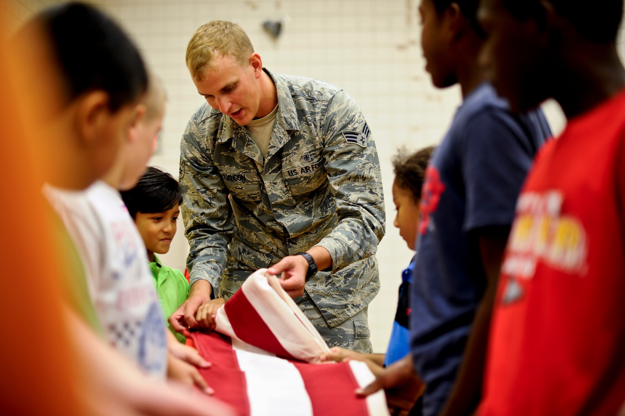 Senior Airman David Clauson, 22nd Force Support Squadron honor guardsman, shows children how to fold the American flag, Aug. 8, 2014, at McConnell Air Force Base, Kan. Base honor guardsmen performed ceremonial demonstrations for children who attended McConnell’s annual Big for a Day event. (U.S. Air Force photo/Airman 1st Class John Linzmeier)