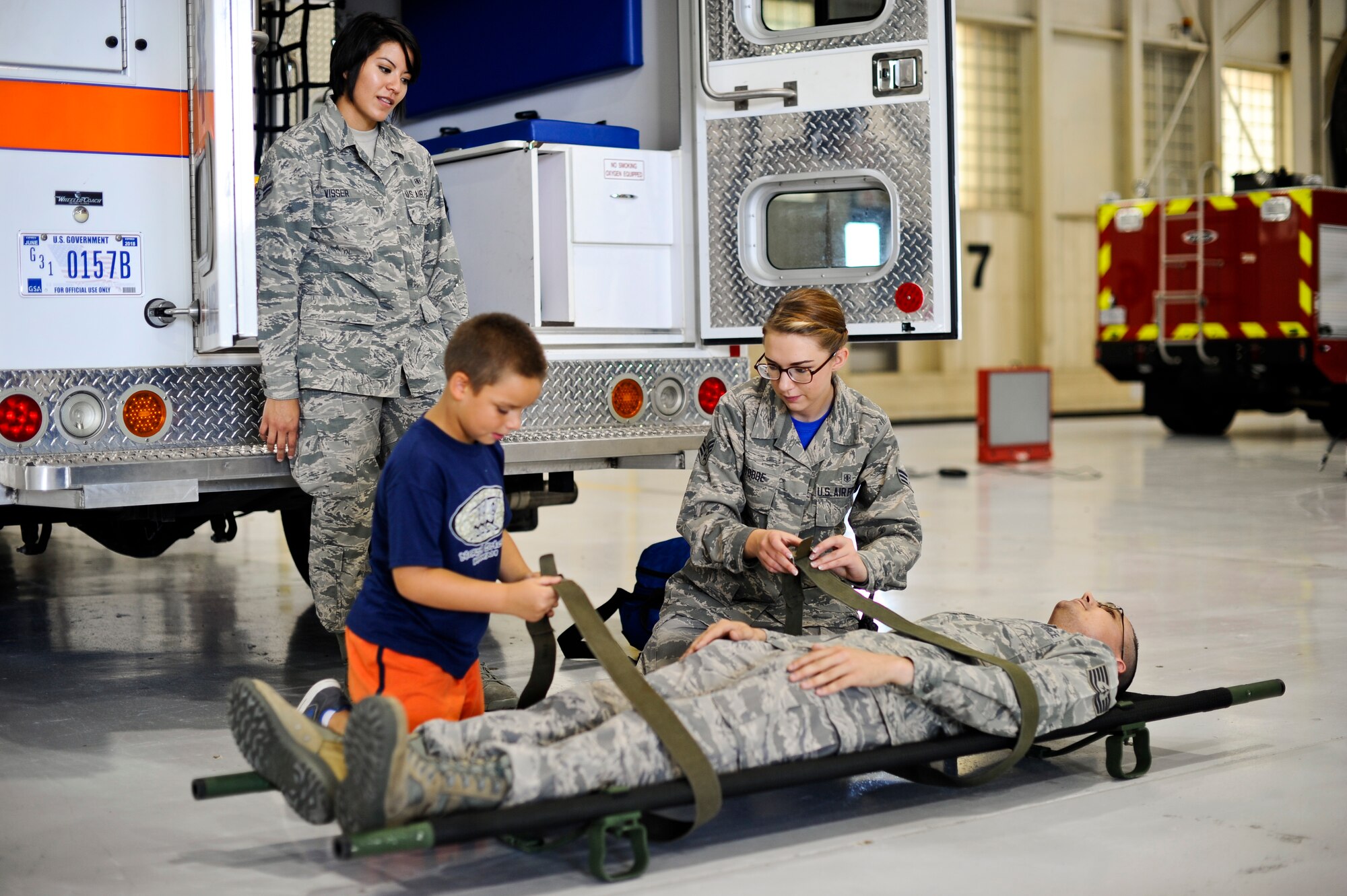 Senior Airman Autumn Stobbe, 22nd Aerospace Medicine Squadron medical technician, shows a boy how to secure a person on a litter during the annual “Big for a Day” event, Aug. 8, 2014, at McConnell Air Force Base, Kan. The 349th Air Refueling Squadron sponsored the event to help children from Big Brothers Big Sisters understand what Airmen do on a daily basis. (U.S. Air Force photo/Airman 1st Class John Linzmeier)
