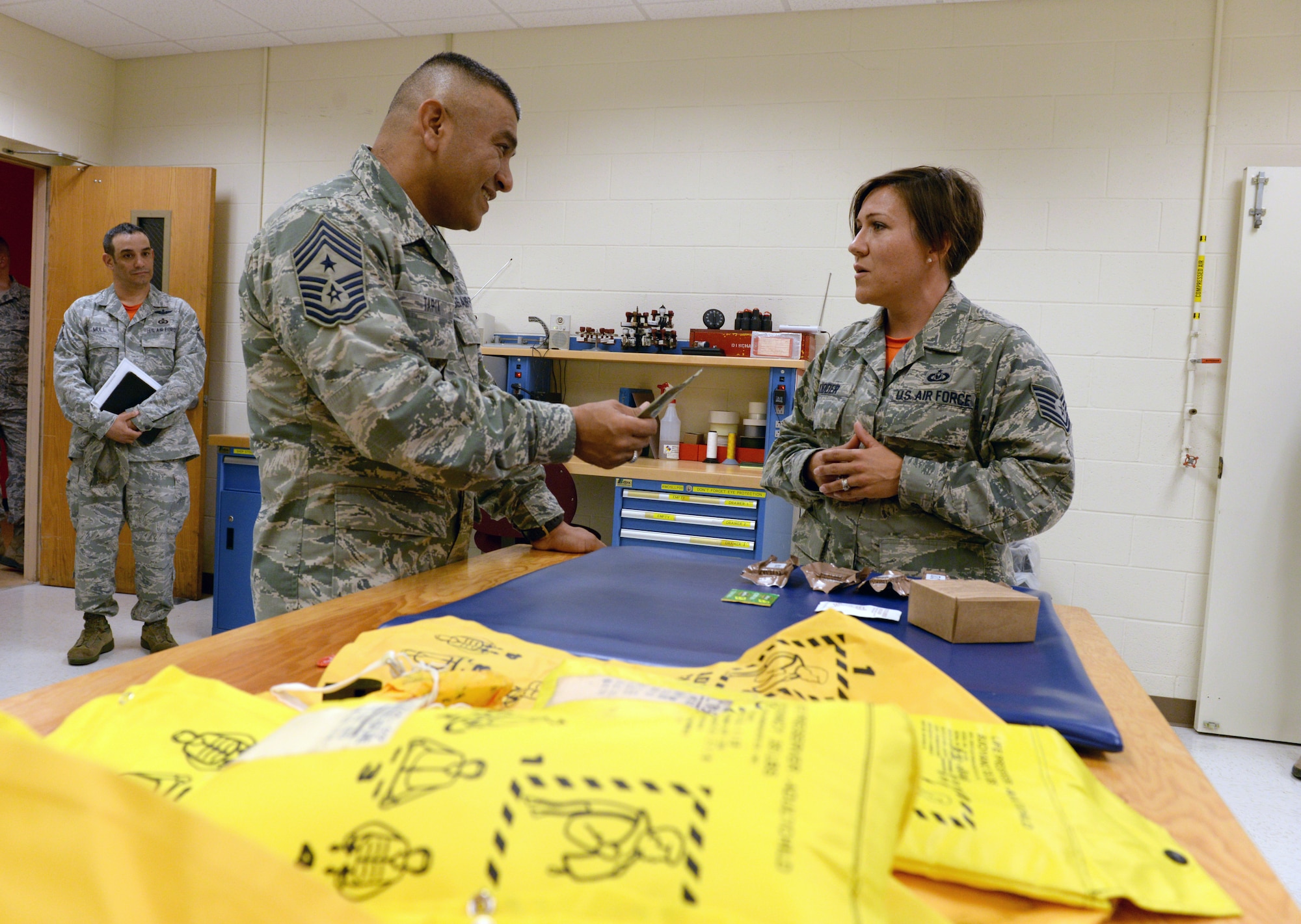 ALTUS AIR FORCE BASE, Okla. – U.S. Air Force Tech. Sgt. Christie Kidder, 97th Operations Support Squadron aircrew flight equipment technician, explains cost-saving initiatives to reduce waste to U.S. Air Force Chief Master Sgt. Gerardo Tapia, command chief of Air Education and Training Command, during Tapia’s visit to the 97th Air Mobility Wing Aug. 8, 2014. The squadron developed an initiative to donate expiring non-perishable food to a nearby food bank. (U.S. Air Force photo by Staff Sgt. Nathanael Callon/Released) 