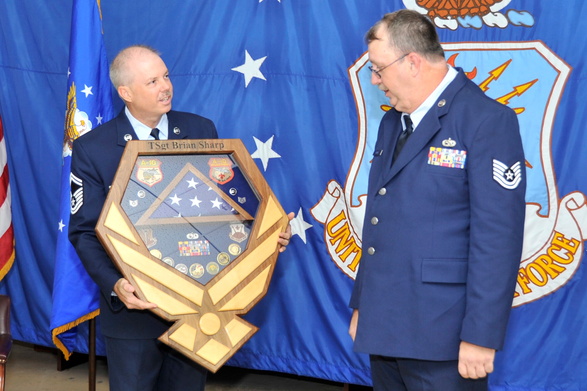 U.S. Air Force Senior Master Sgt. Ron Harsen, aircraft fabrication superintendent, 307th Maintenance Squadron, presents a shadow box to Tech. Sgt. Brian Sharp during a retirement ceremony at Barksdale Air Force Base, La., Aug. 2, 2014. Sharp retired with more than 27 years of service. (U.S. Air force photo by Master Sgt. Jeff Walston/Released)