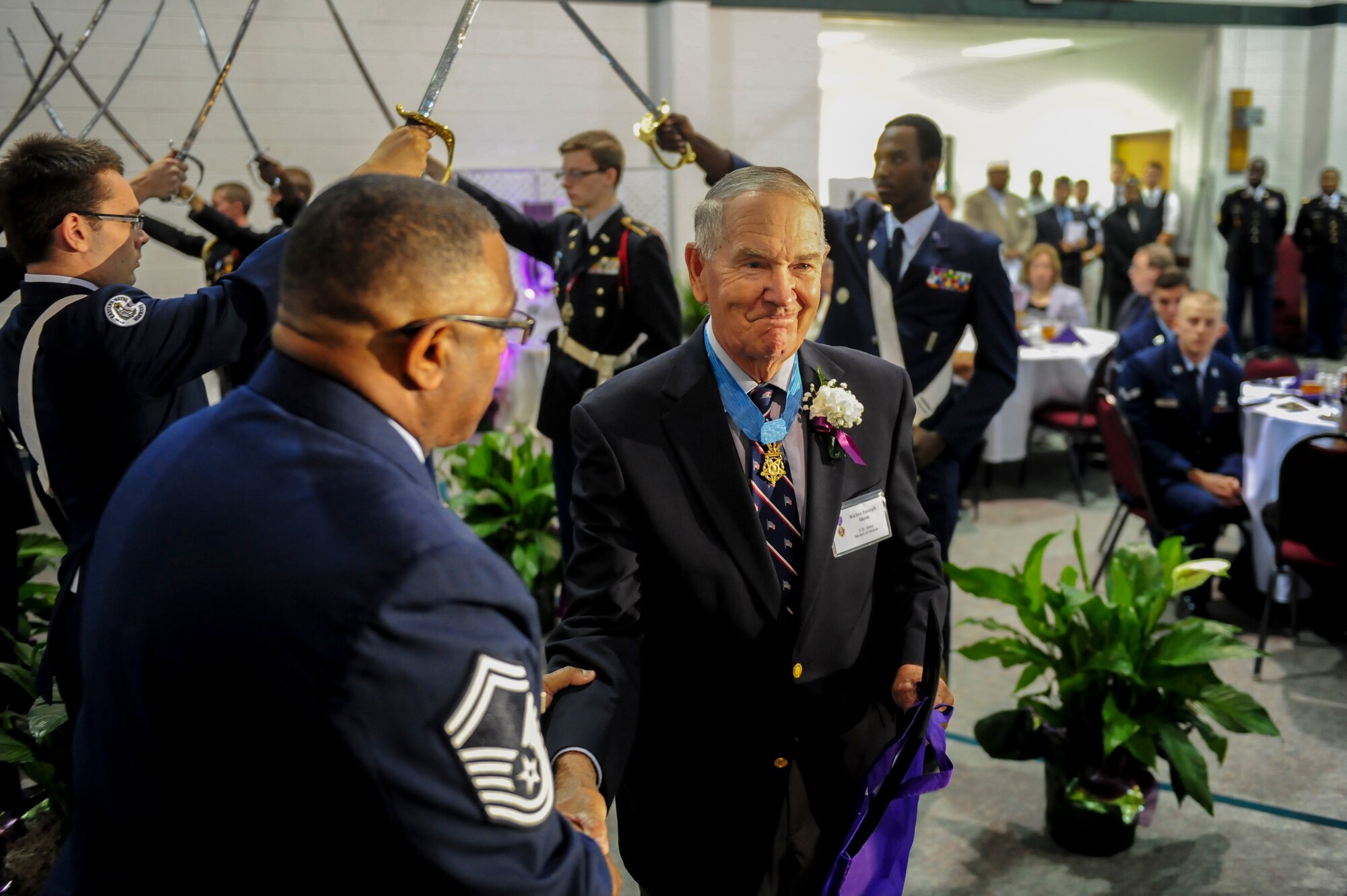 Retired U.S. Army Col. Walter Marm passes through the “Walk of Honor” during a Purple Heart Banquet, Aug. 7, 2014, at the First Pentecostal Holiness Church in Goldsboro, North Carolina. The “Walk of Honor,” which is formed by a line of local JROTC cadets with sabers drawn, spotlights each medal recipient as they are introduced to the audience. (U.S. Air Force photo/Airman 1st Class Brittain Crolley)
