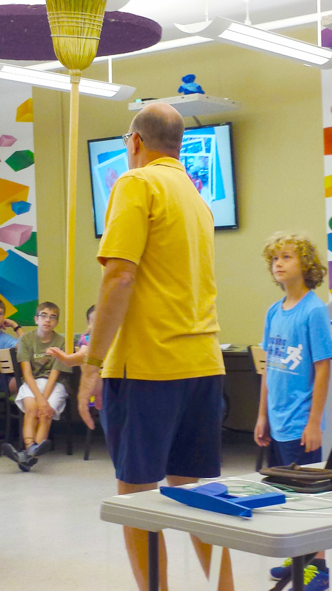 Professor Billy Hix (holding the broom), a Science, Technology, Engineering and Math (STEM) educator, explains the “Mass always leads” concept to Caleb Voorhes-Fontenot (right) during the first day of the Arnold Engineering Development Complex (AEDC) STEM Camp. The concept helps demonstrate rocket stability. (Photo by Jere Matty)