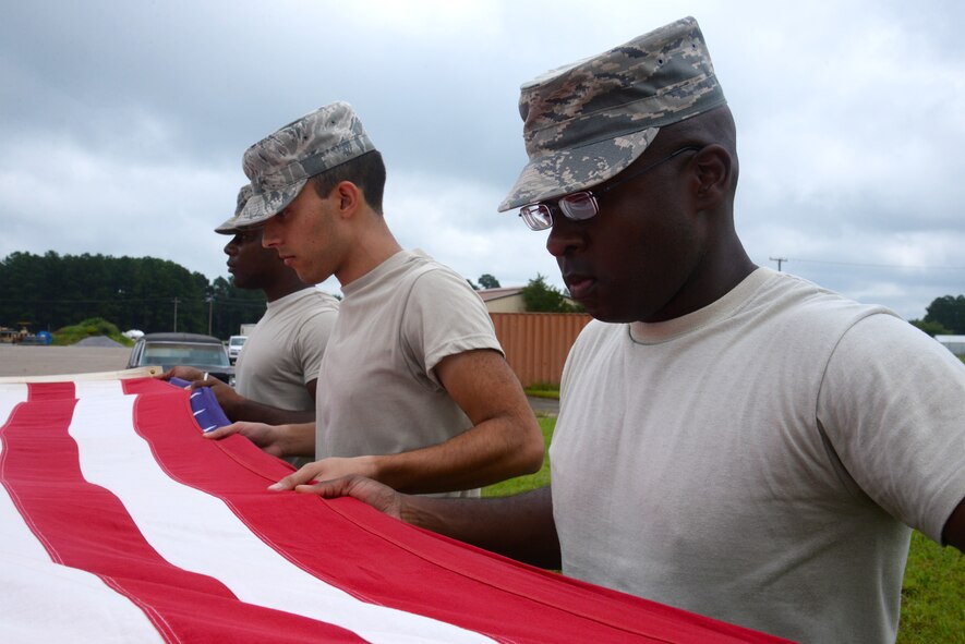 U.S. Air Force Senior Airman Calvert Smith, 20th Aircraft Maintenance Squadron 55th Aircraft Maintenance Unit, tactical aircraft maintainer (right), practices folding a flag with the honor guard at Shaw Air Force Base, S.C., Aug., 11, 2014. Smith, a San Antonio, Texas, native, has been in the Air Force for more than two years, Shaw is his first duty station. (U.S. Air Force photo by Airman 1st Class Jonathan Bass/Released)