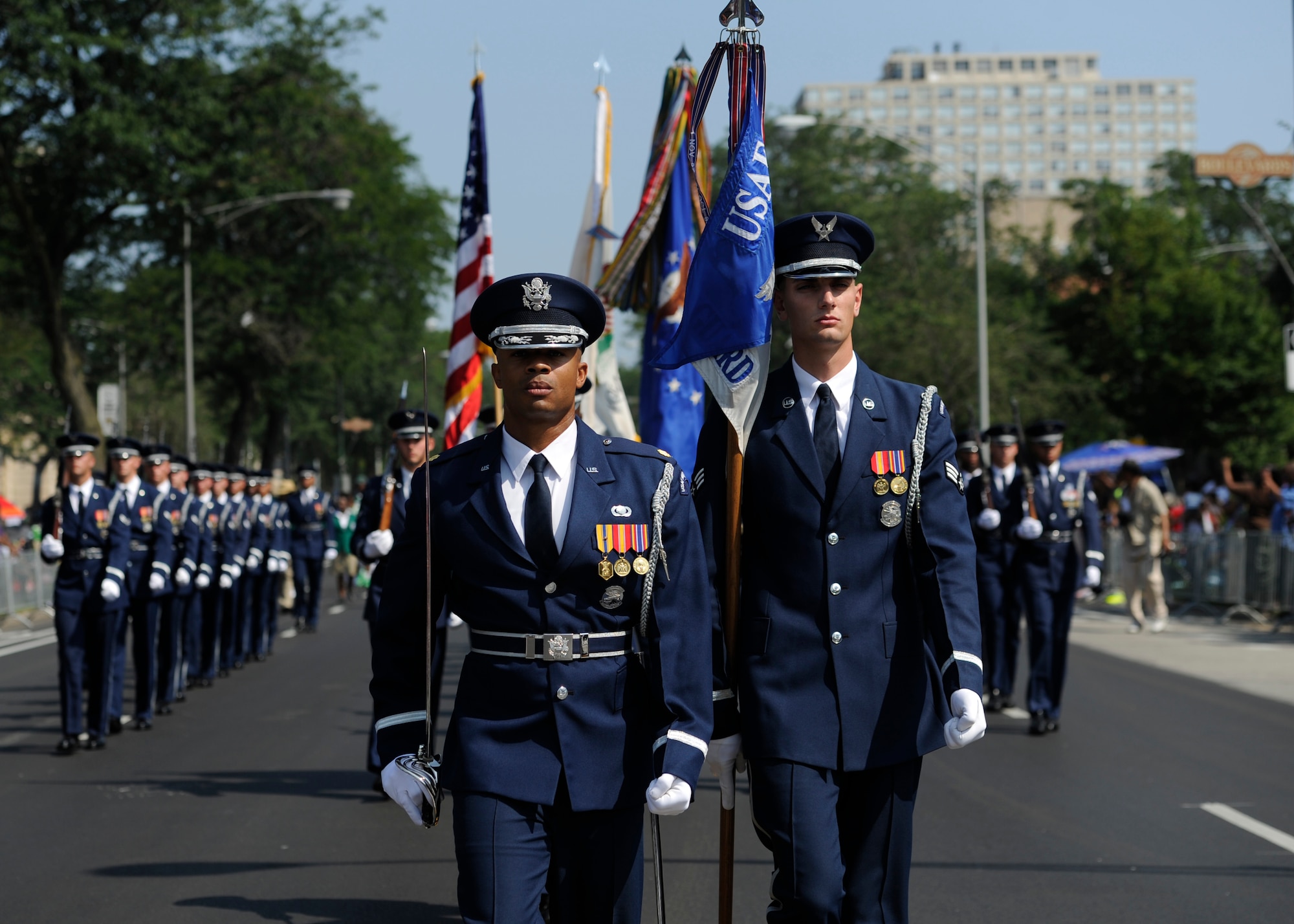 Maj. Scott Belton and Senior Airman Nicholas Priest lead the United States Air Force Color Team and ceremonial guardsmen during the Bud Billiken Parade in Chicago, Il., August 9, 2014.  Belton is the Assistant Director of Operations and Priest is a member of the Color Flight Team within the USAF Honor Guard. (U.S. Air Force photo/ Senior Airman Nesha Humes)
