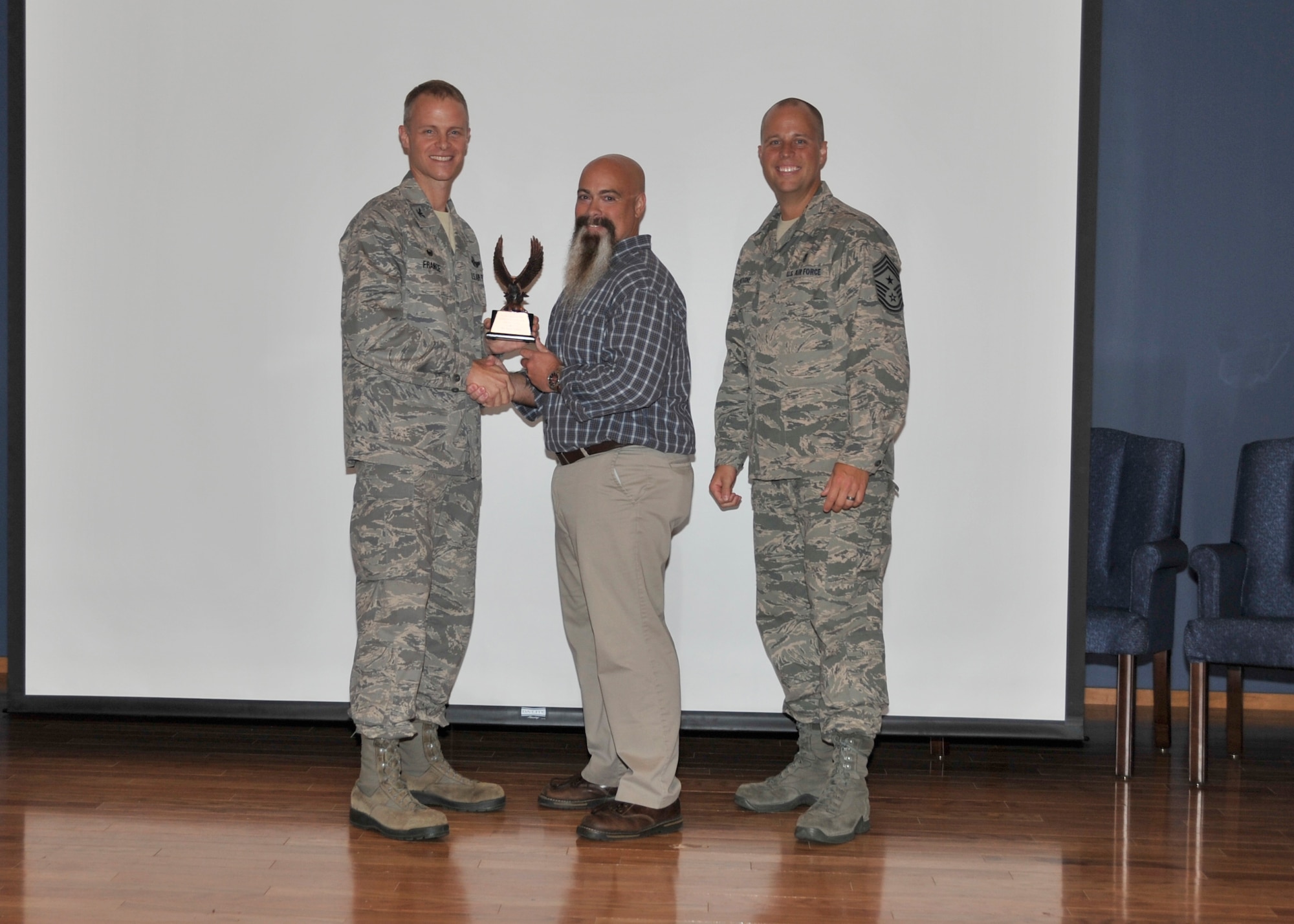 Col. Derek France, 325th Fighter Wing commander, congratulates Todd Bailey, an operations training specialist assigned to Air Forces Northern’s Operations Directorate, on his Team Tyndall-level award for Tenant Unit Civilian of the Quarter, Category II. On the other side of Bailey is 325th FW Command Chief Master Sgt. Christoper Lantagne. Bailey was lauded for his exceptional skills managing readiness issues and his ongoing commitment to higher education, recently earning academic distinction finishing among the top 25 percent of his class. Also selected for a Team Tyndall-level award in the Company Grade Officer of the Quarter category was Capt. Matthew Shemo, a search and rescue duty officer with the Air Force Rescue Coordination Center who was unable to attend the ceremony. He was recognized for his superb management of more than 1300 potential distress cases and for completion of a rigorous Firefighter, First Responder and  CPR course which resulted in his certification as State of Florida Firefighter. (Photo by A1C Solomon)