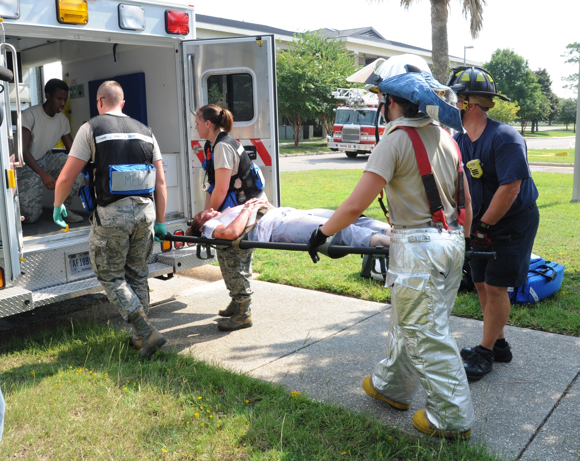 Members from the Keesler fire department and the 81st Medical Group load a “victim” into the back of an ambulance for transportation to the medical center during a major accident response exercise Aug. 7, 2014, at the Locker House at Keesler Air Force Base, Miss. Team Keesler practiced real-world training during the exercise which simulated a gas line explosion that set a building on fire. Due to the extreme temperatures, exercise “players” wore minimal fire gear.  (U.S. Air Force photo by Kemberly Groue)