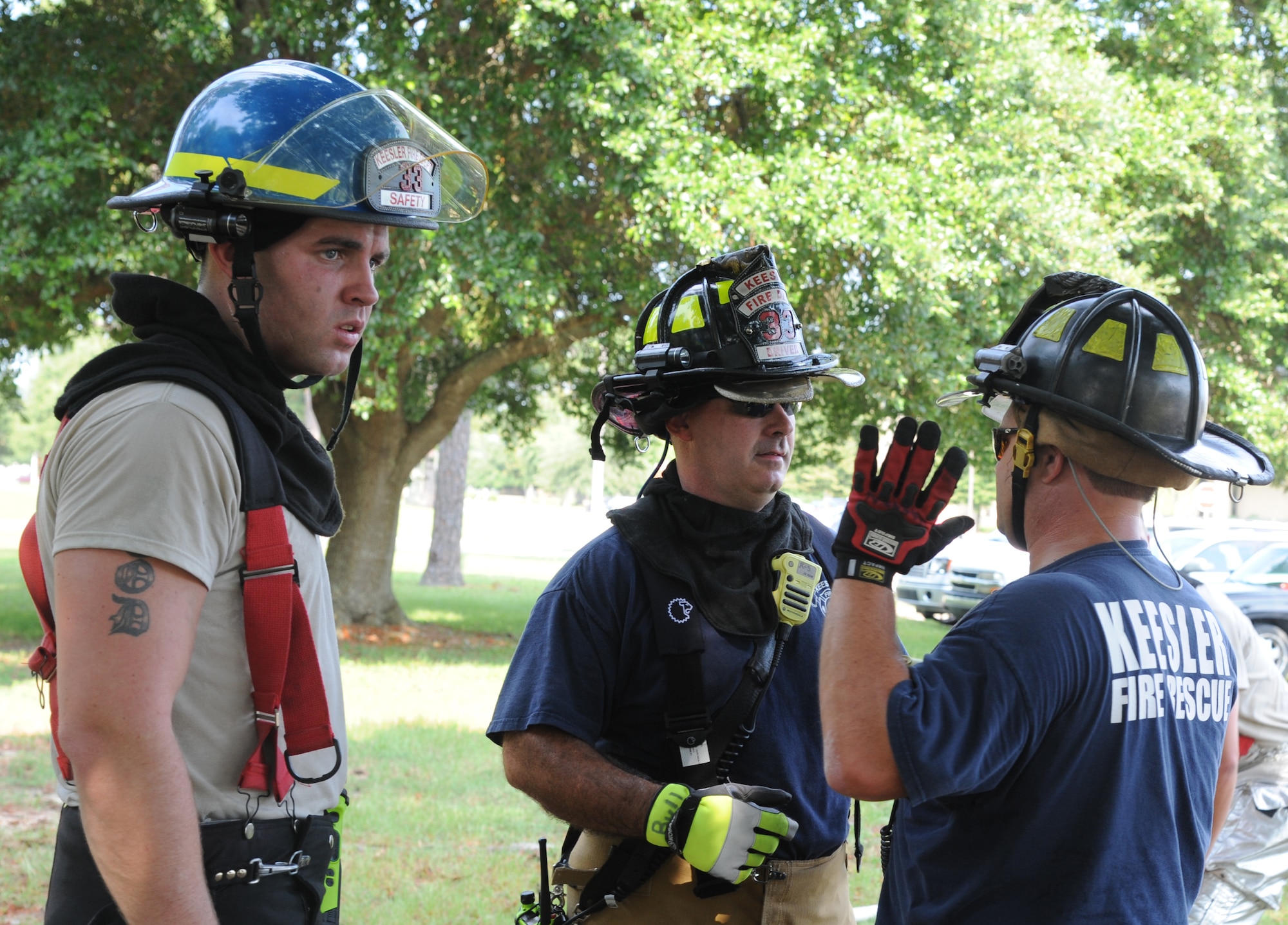 Staff Sgt. John Hood, Jerame Bullard and Chad Martin, Keesler firefighters, have a discussion during a major accident response exercise Aug. 7, 2014, at the Locker House at Keesler Air Force Base, Miss. Team Keesler practiced real-world training during the exercise which simulated a gas line explosion that set a building on fire. Due to the extreme temperatures, exercise “players” wore minimal fire gear.  (U.S. Air Force photo by Kemberly Groue)