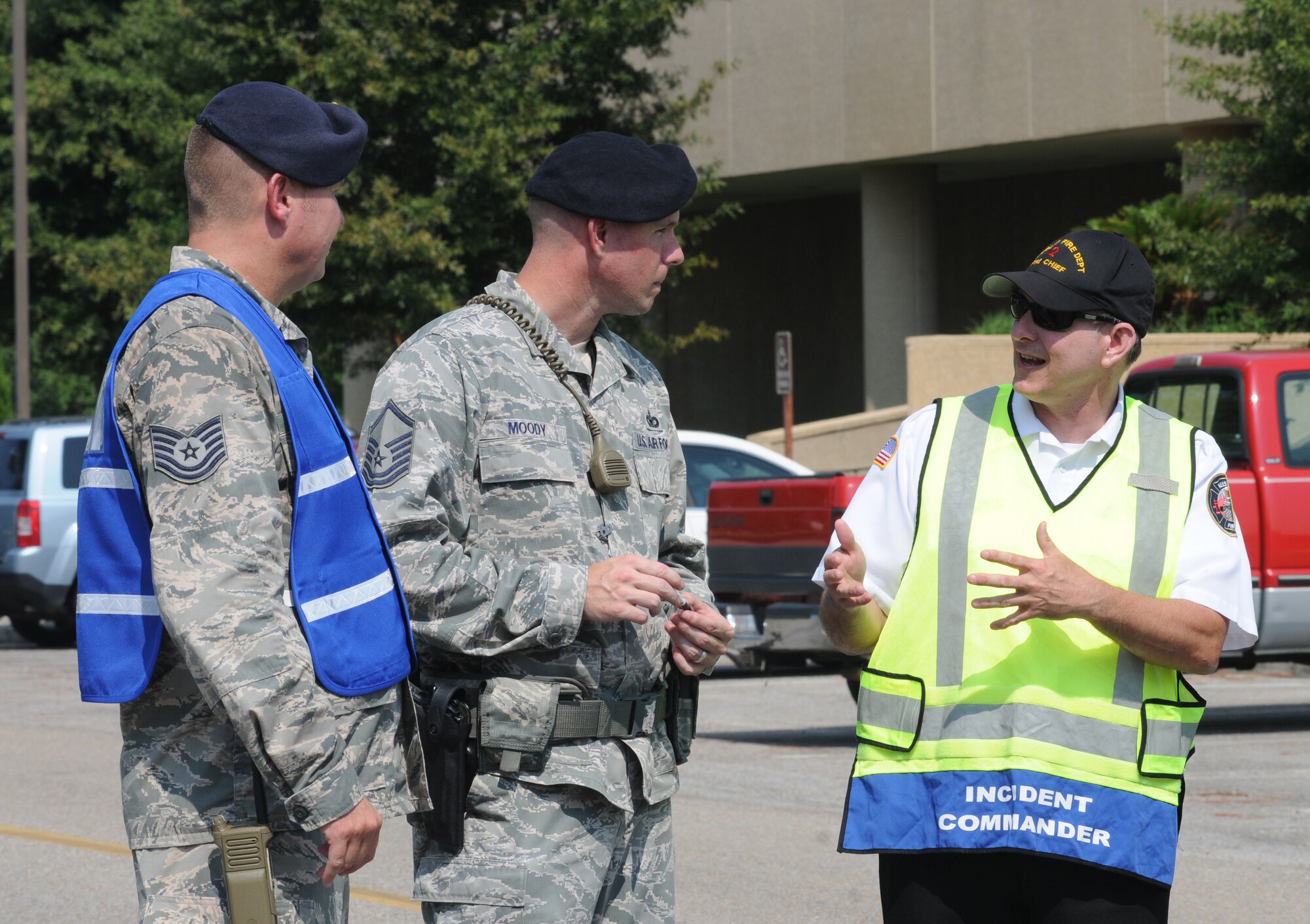 Tech. Sgt. Aaron Gaddis and Master Sgt. Jeffrey Moody, 81st Security Forces Squadron, and Chief James Donnett, Keesler fire chief, have a discussion during a major accident response exercise Aug. 7, 2014, at the Locker House at Keesler Air Force Base, Miss. Team Keesler practiced real-world training during the exercise which simulated a gas line explosion that set a building on fire.  (U.S. Air Force photo by Kemberly Groue)
