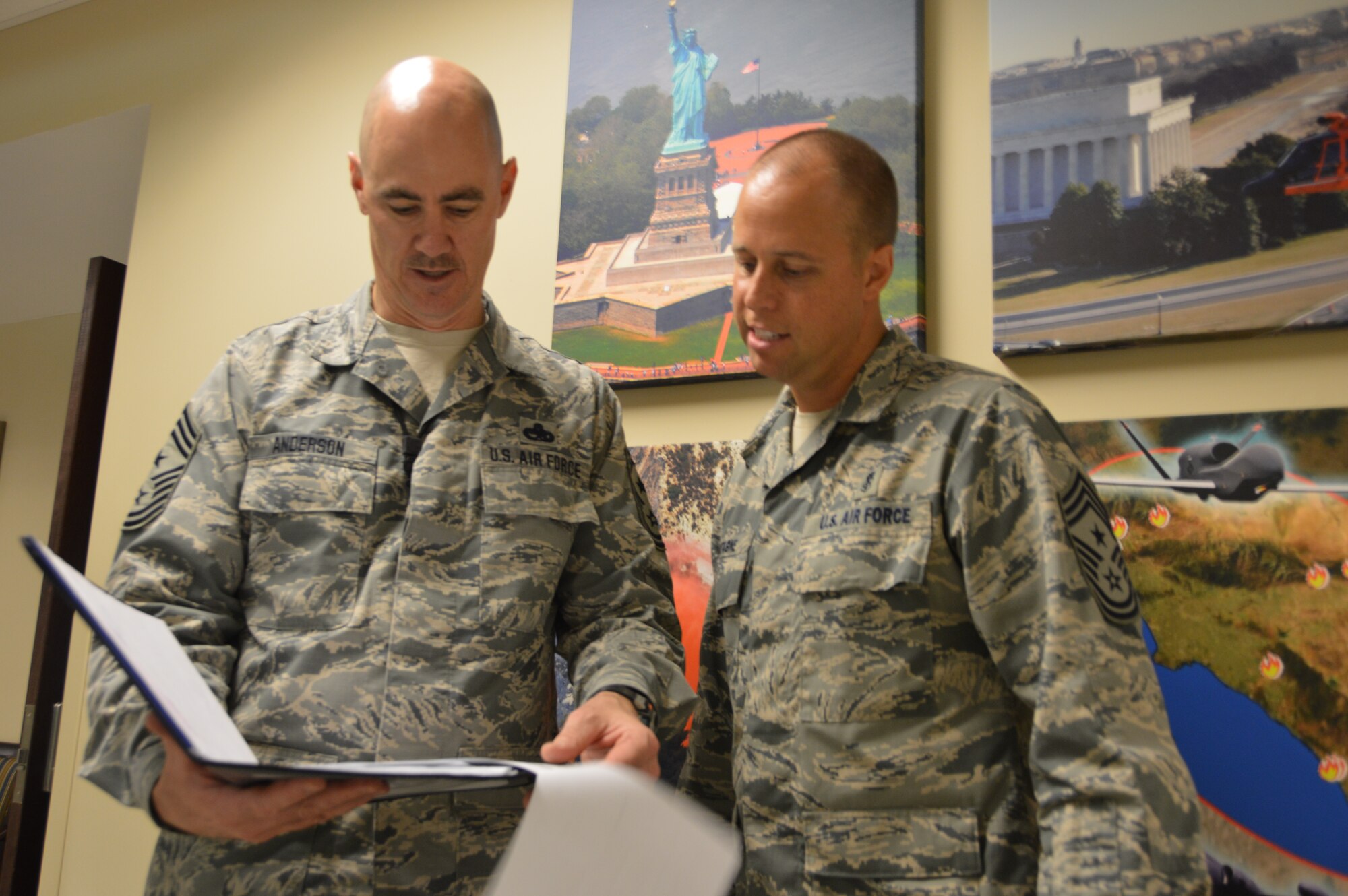 Chief Master Sgt. Ronald Anderson, Continental U.S. North American Aerospace Defense Region-1st Air Force (Air Forces Northern) Command Chief, goes over his daily briefing book with Chief Master Sgt. Christopher Latagne, 325th Fighter Wing Command Chief, during a July 30 familiarization tour. While here,  Latagne received a mission briefing, visited various directorates, and had an informal lunch with enlisted members of the organization. (Photo by Mary McHale)